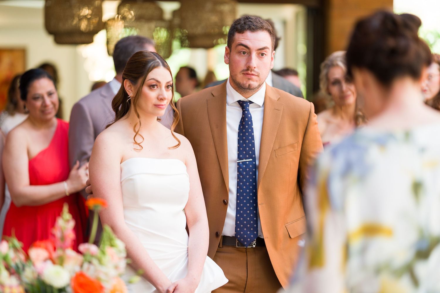 Wedding party members in colorful dresses pose together at an outdoor venue.