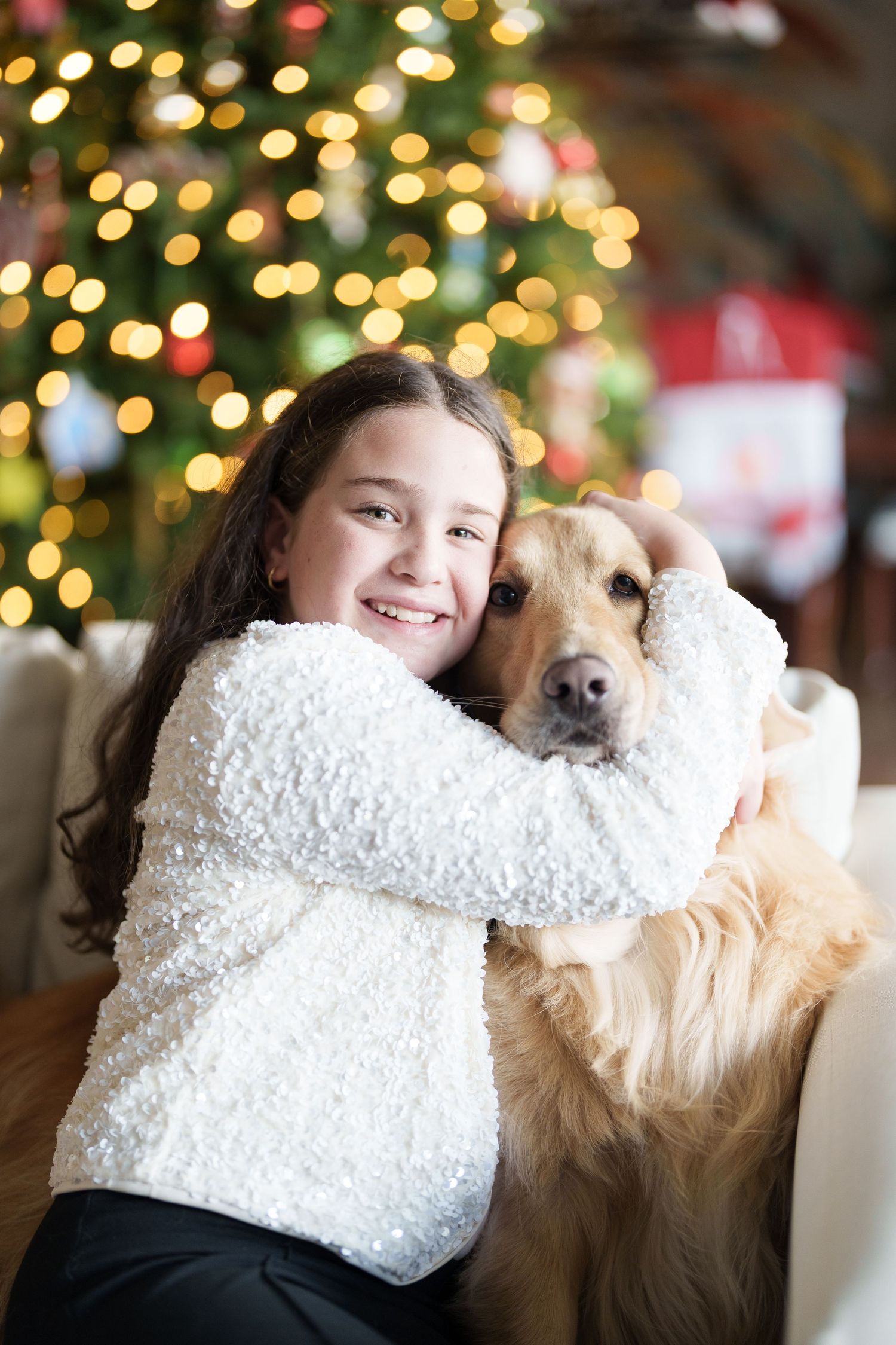 A cozy Christmas scene with a golden retriever and fuzzy white sweater against twinkling holiday lights.