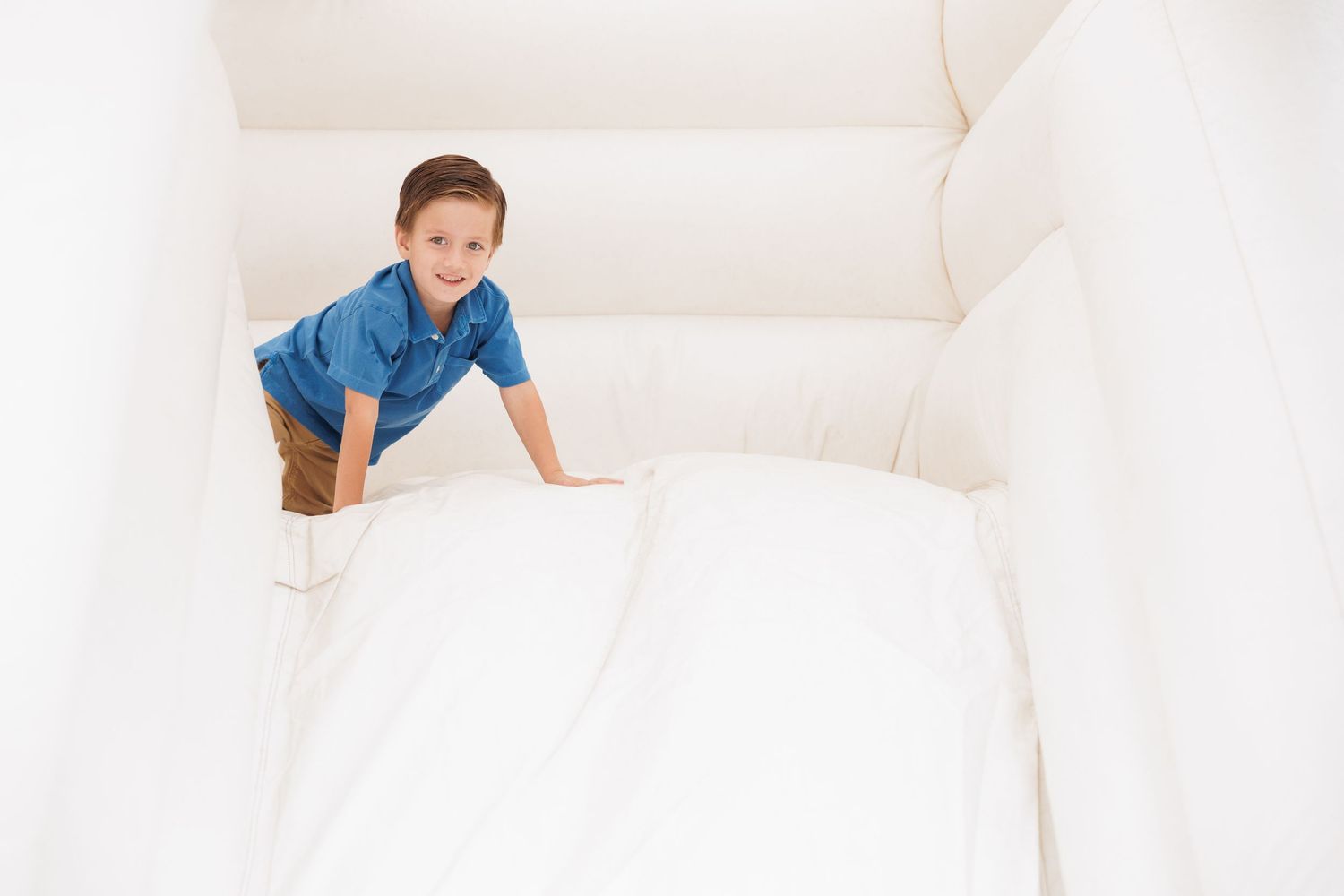 Child climbing on white inflatable bounce house or play structure.