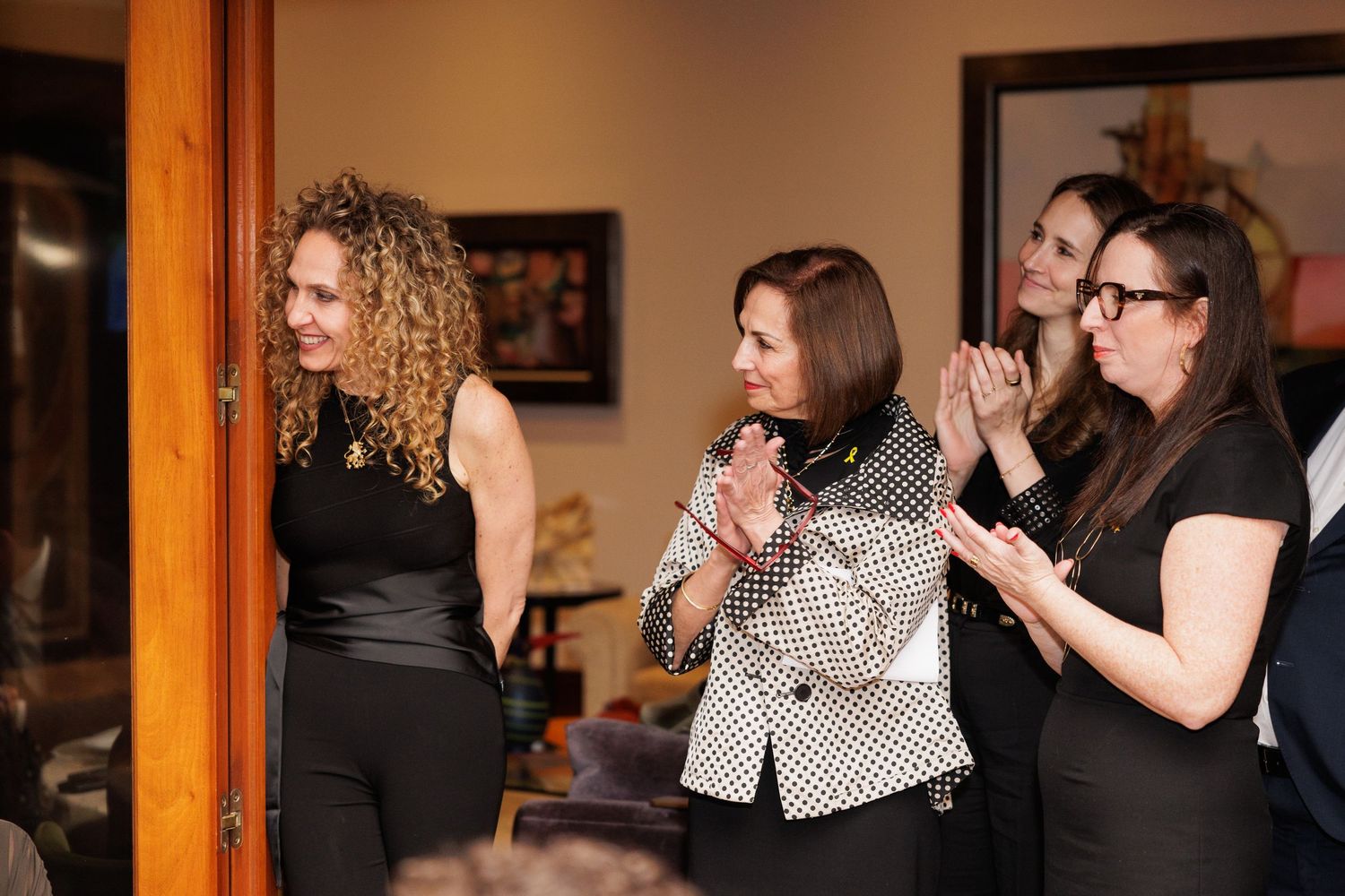 A group of women react excitedly during an indoor event.