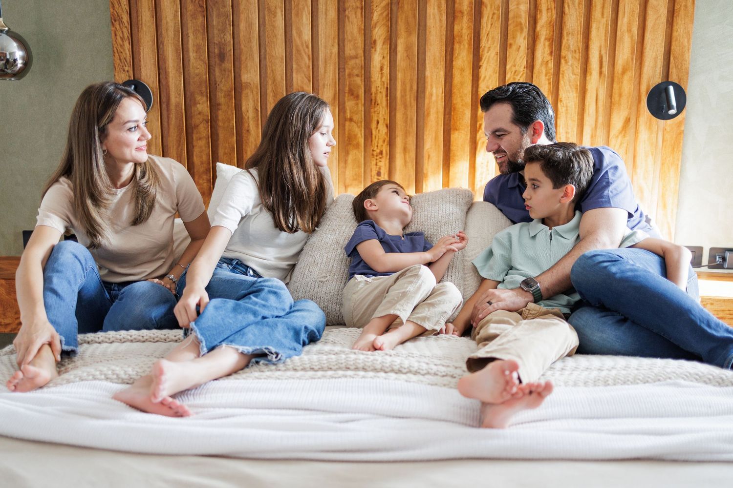 Candid family moments captured while relaxing together on white bedding in a bright interior setting.