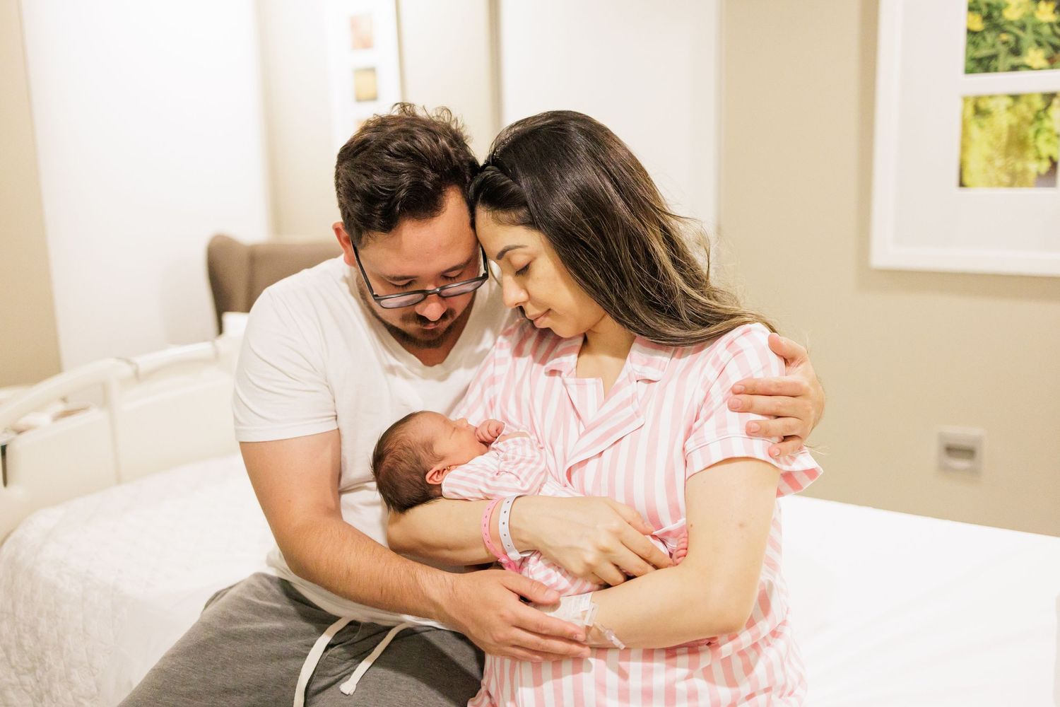 Family bonding moments with newborn baby in bright sunlit room.