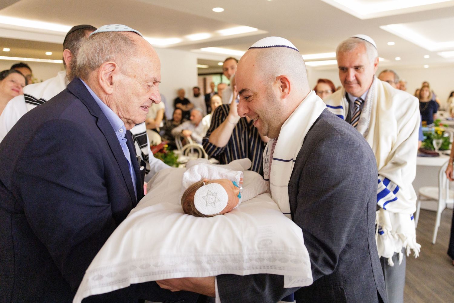 Two men examine a ceremonial object on a white pillow during a religious celebration.