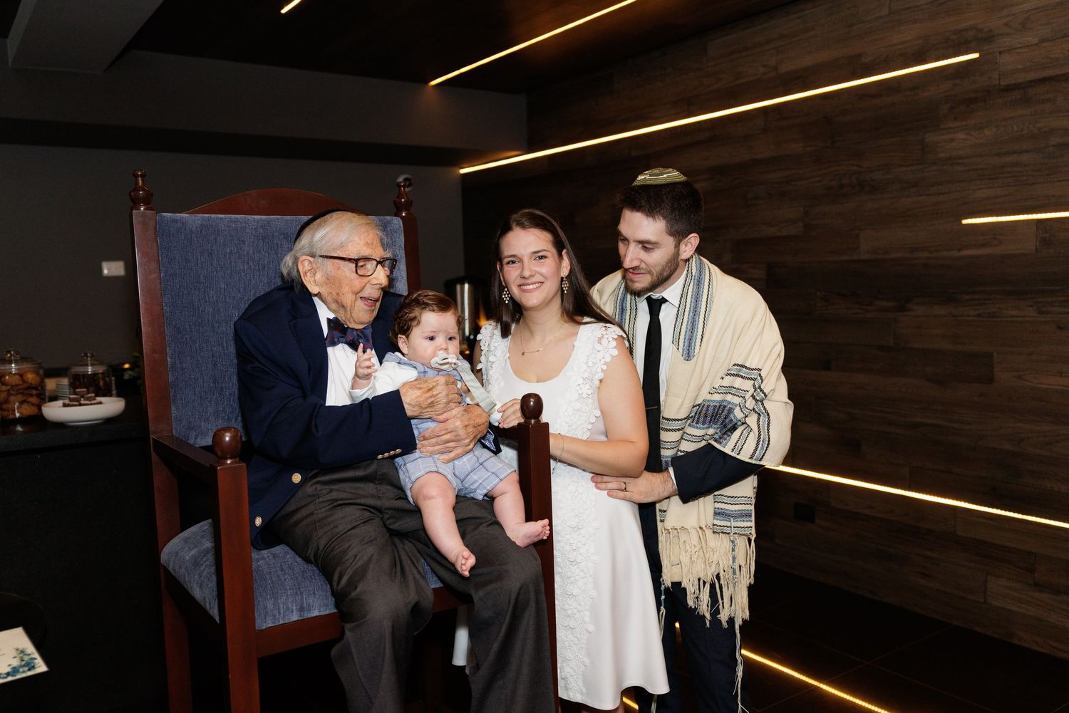 A family celebrates together in an indoor venue with dark wood paneling.