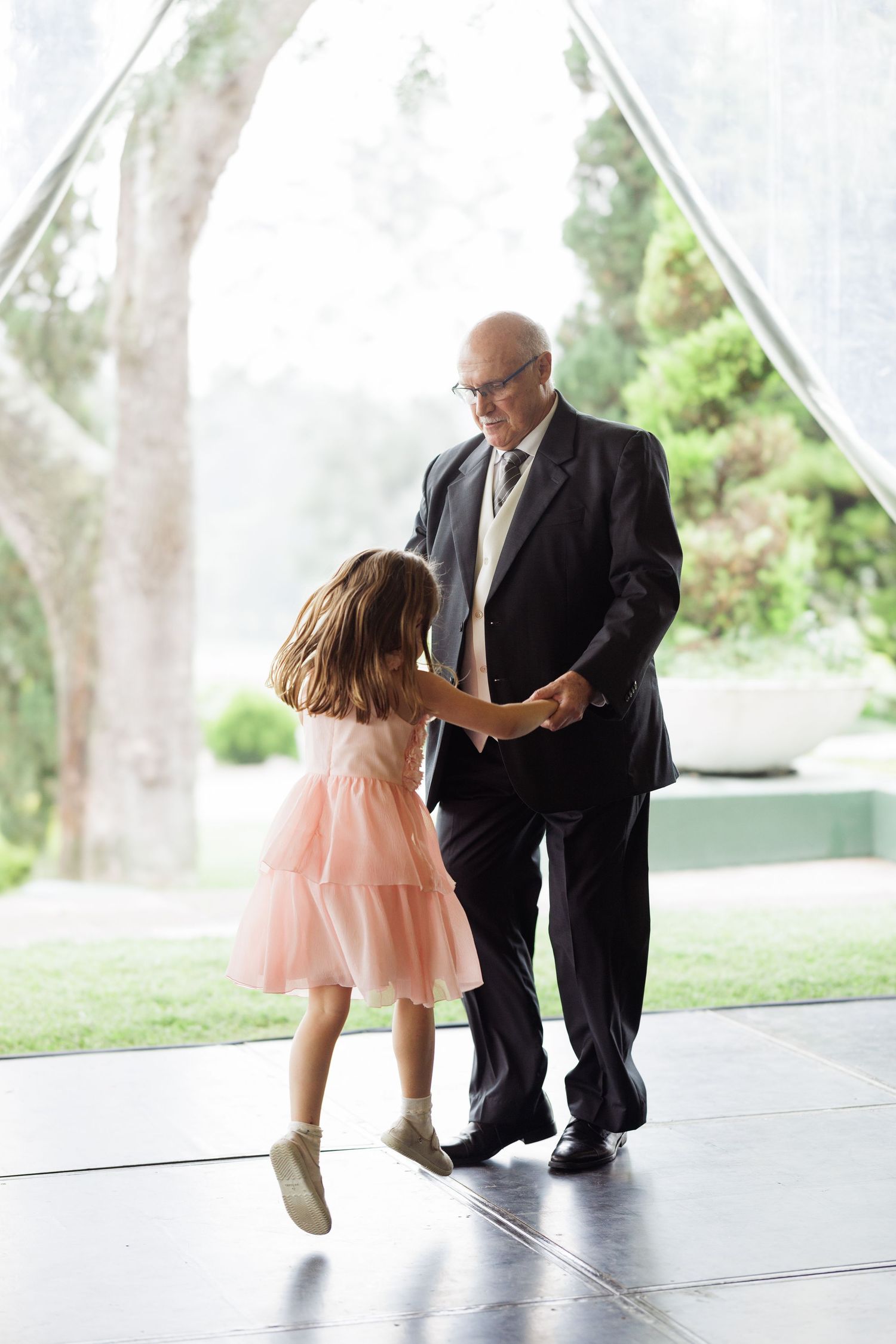 Progressive shots of a dance routine on an outdoor covered platform with greenery in background.