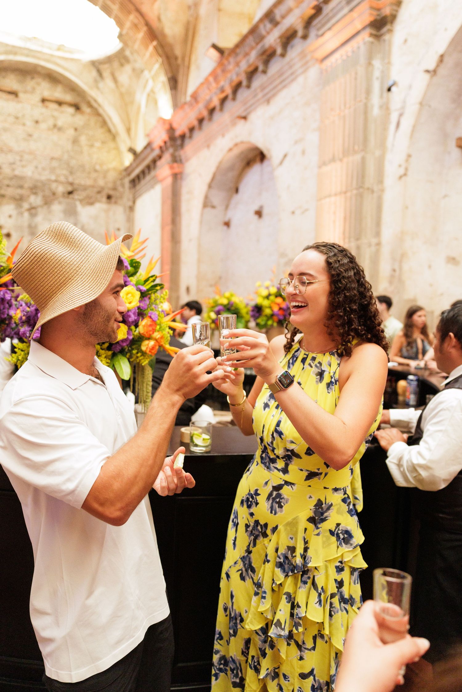Party guests sharing drinks and toasting at an elegant event with floral decorations.