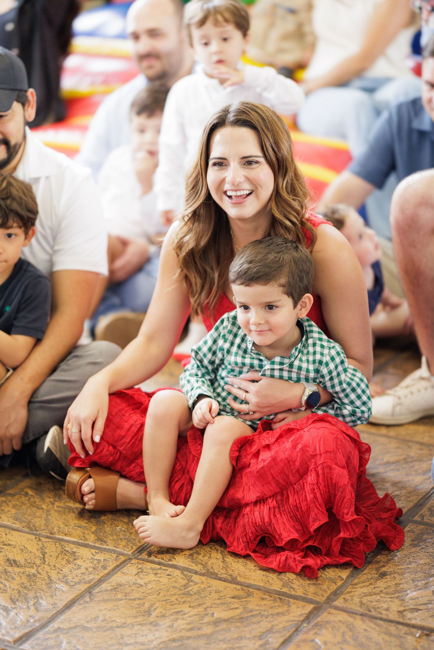 Family gathering on stone floor with festive red and green holiday attire.