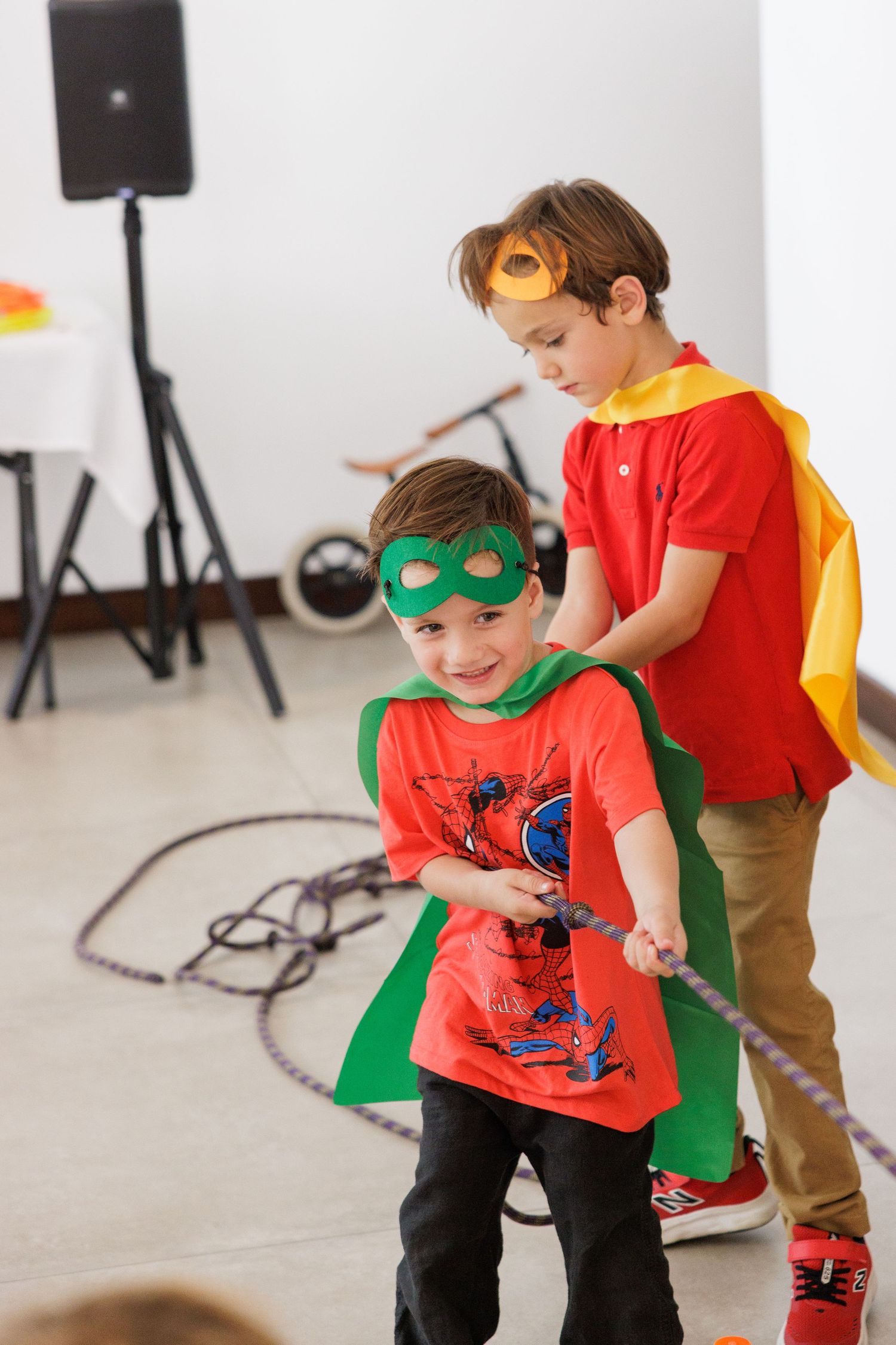 Two children playing dress-up in superhero costumes and masks indoors.