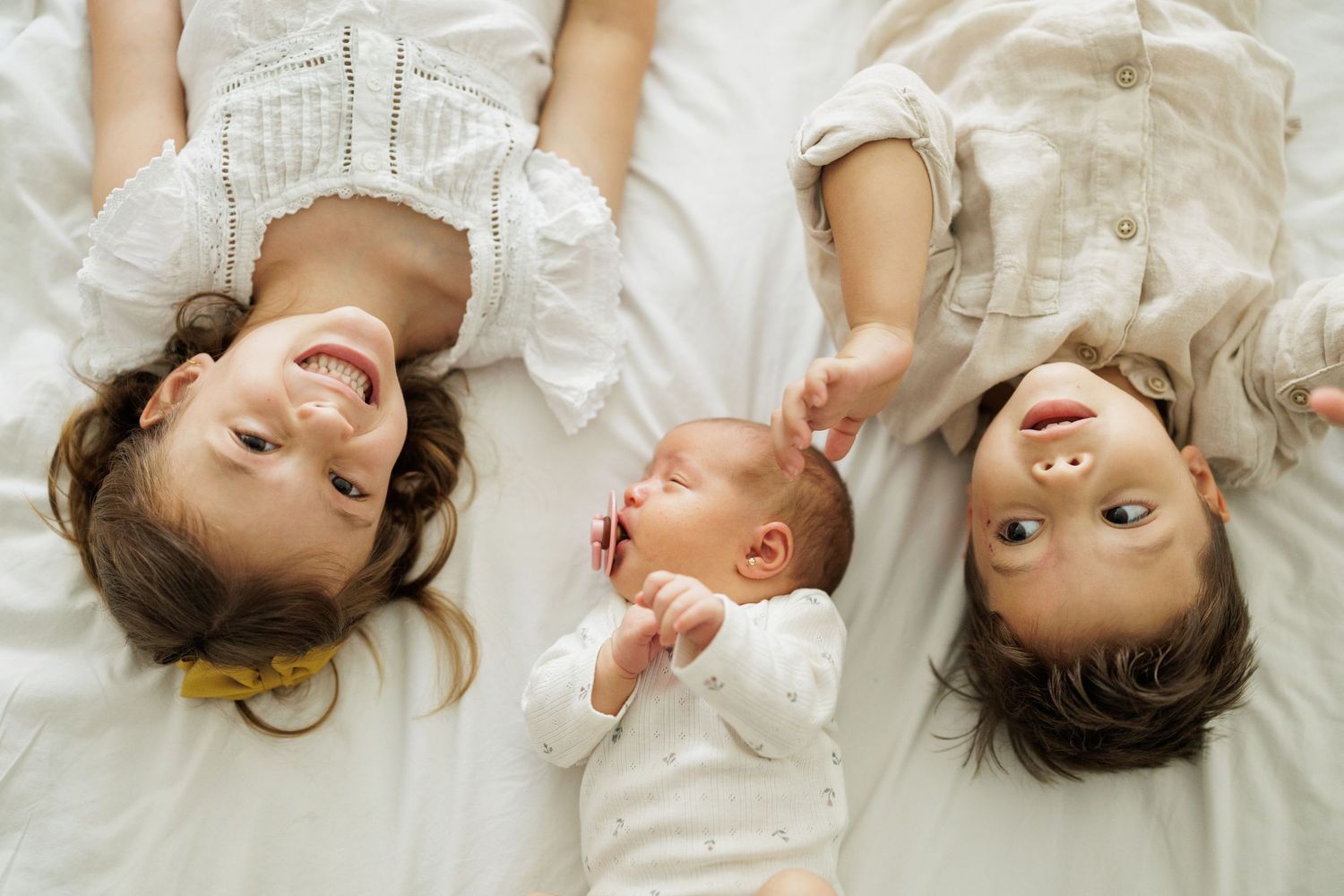 Collection of joyful expressions captured on white bedding in natural light.