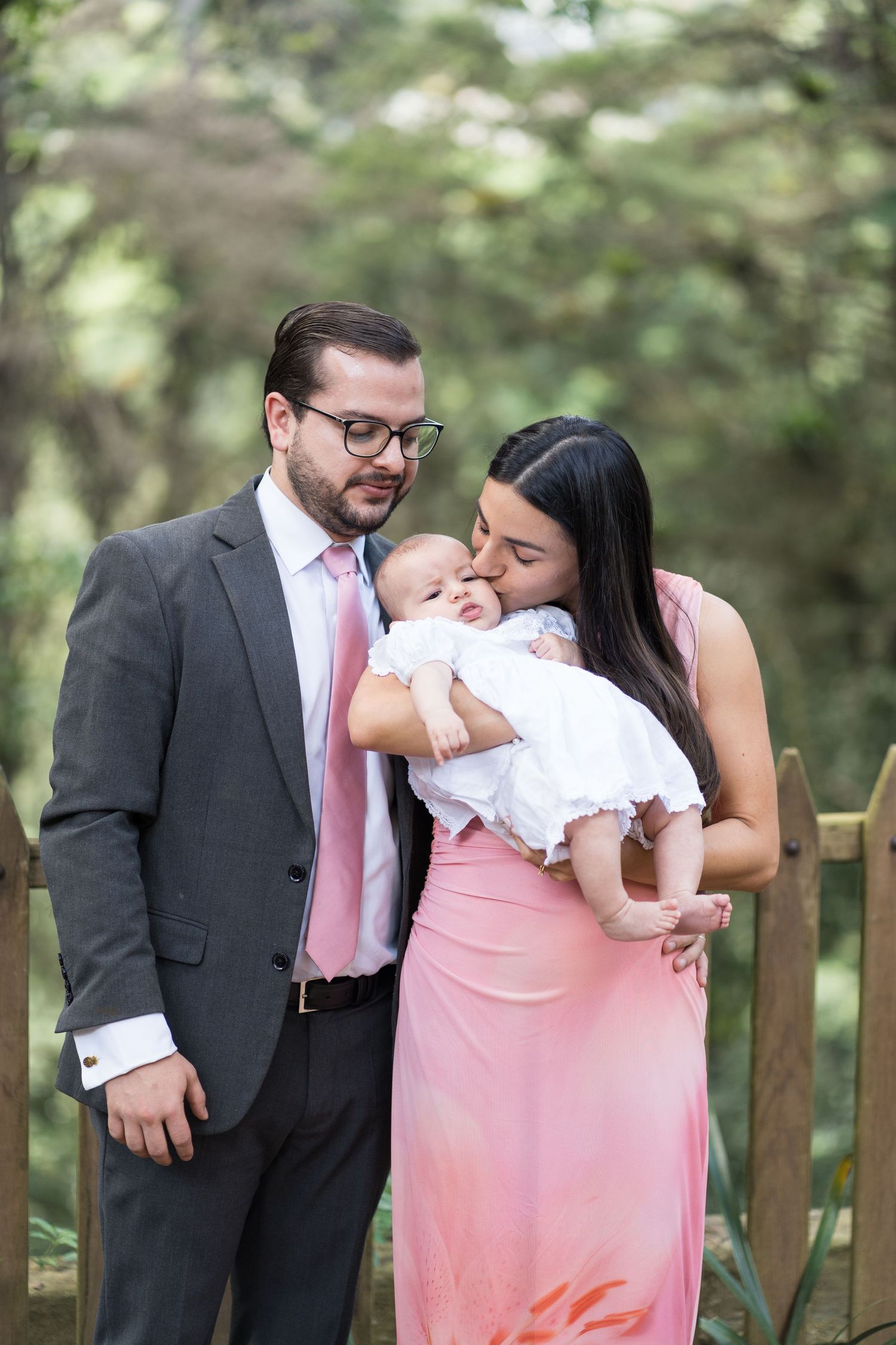A family shares tender moments together in an outdoor garden setting with wooden fence.