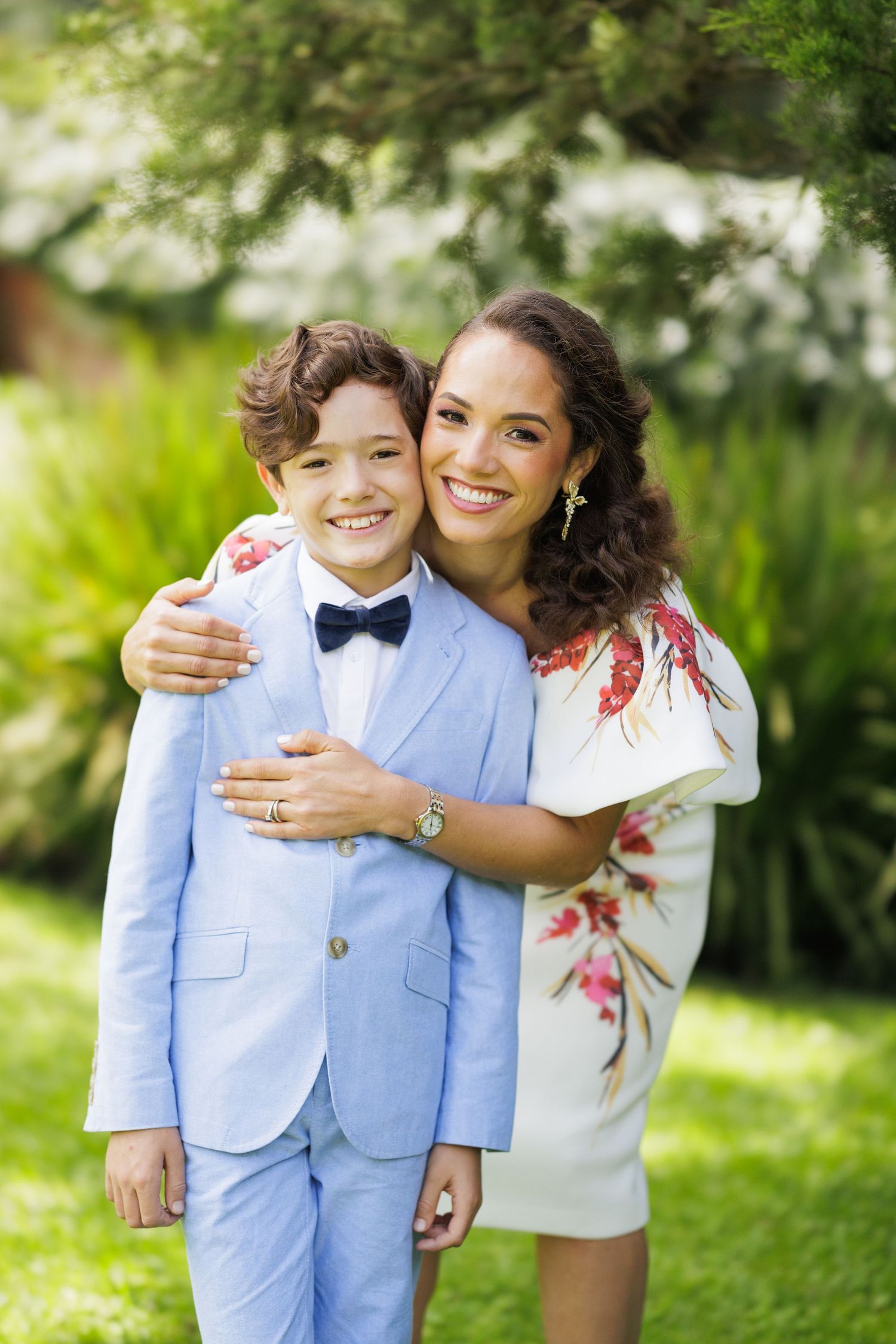 Two people share a tender moment outdoors wearing light blue and floral attire.