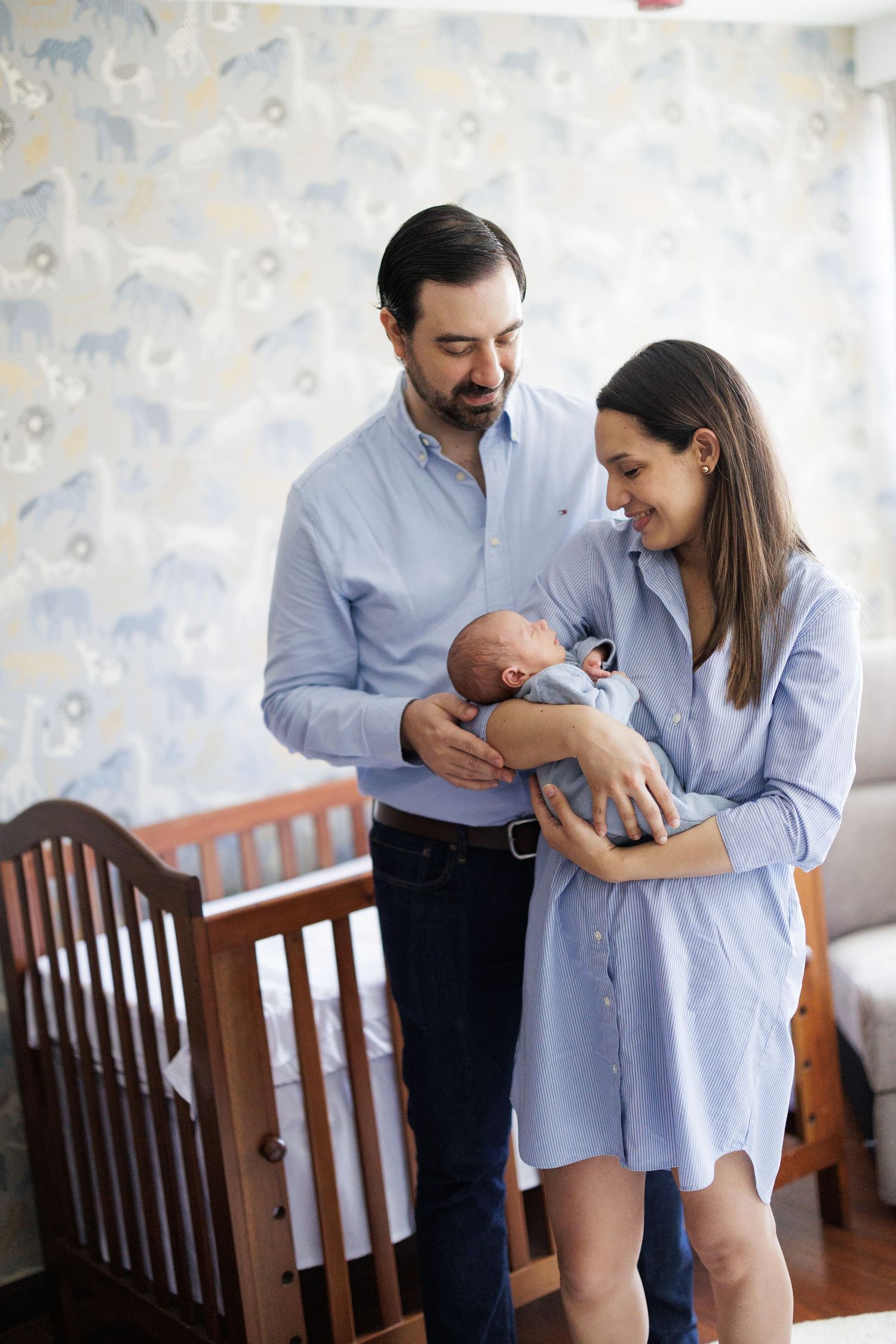 A series of loving family moments in a nursery with blue wallpaper.