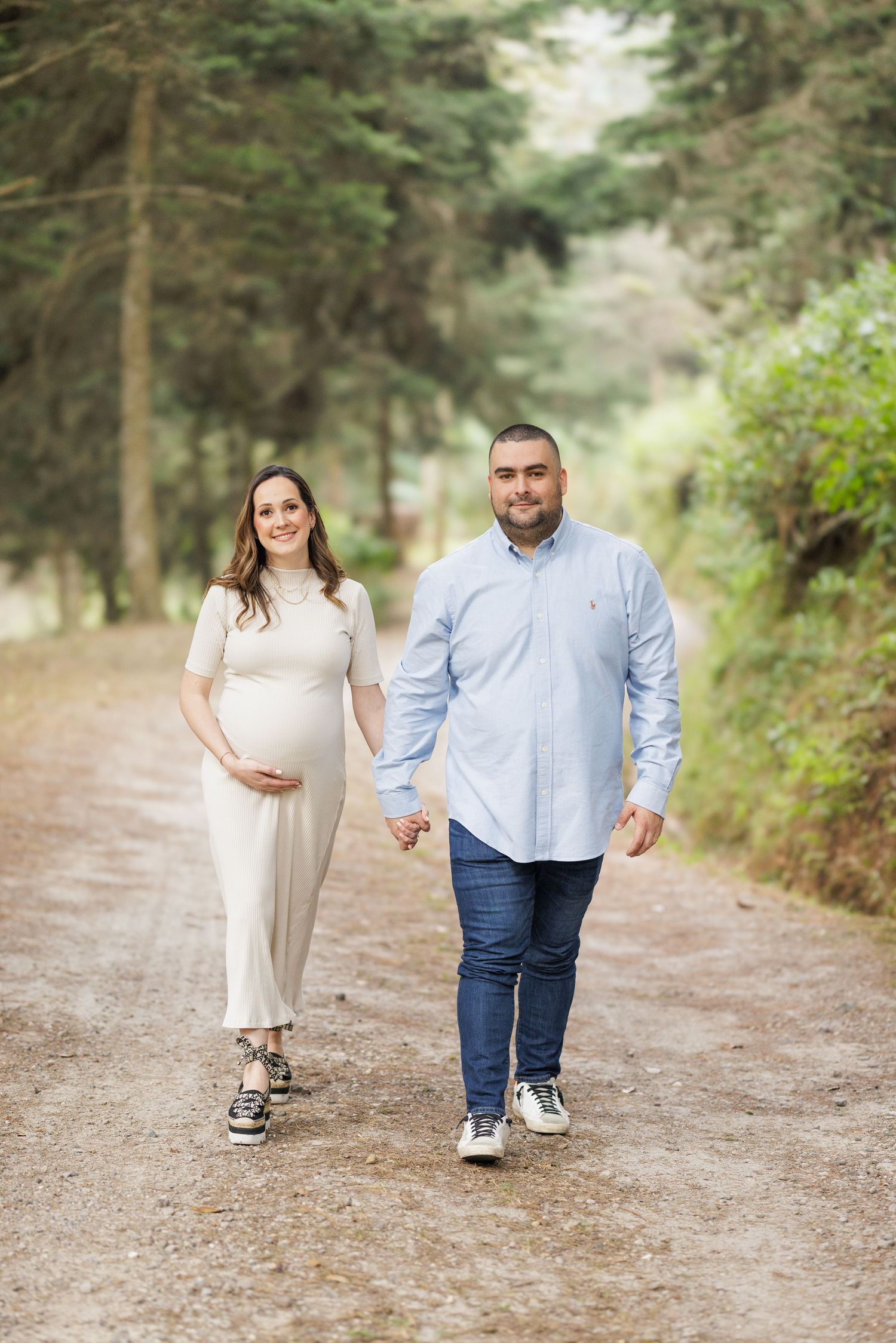 Couple walking hand in hand down a tree-lined dirt path.