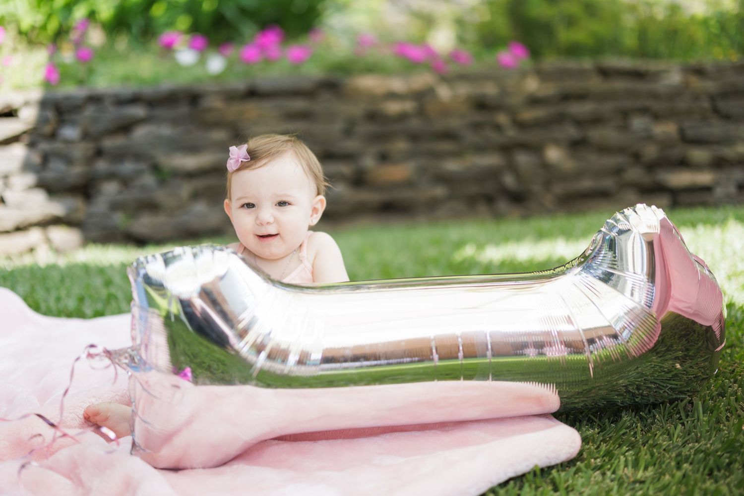 Silver and pink decorative elements arranged on green grass for a party setup.