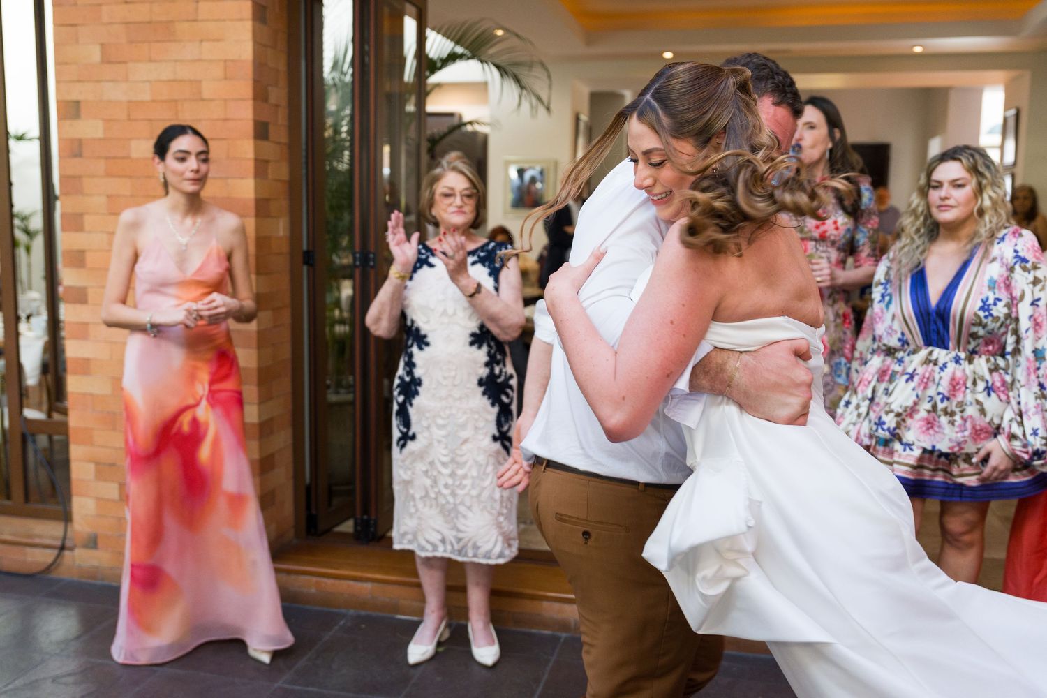 Couples dancing together at a wedding reception in a brick-walled venue with elegant decor.