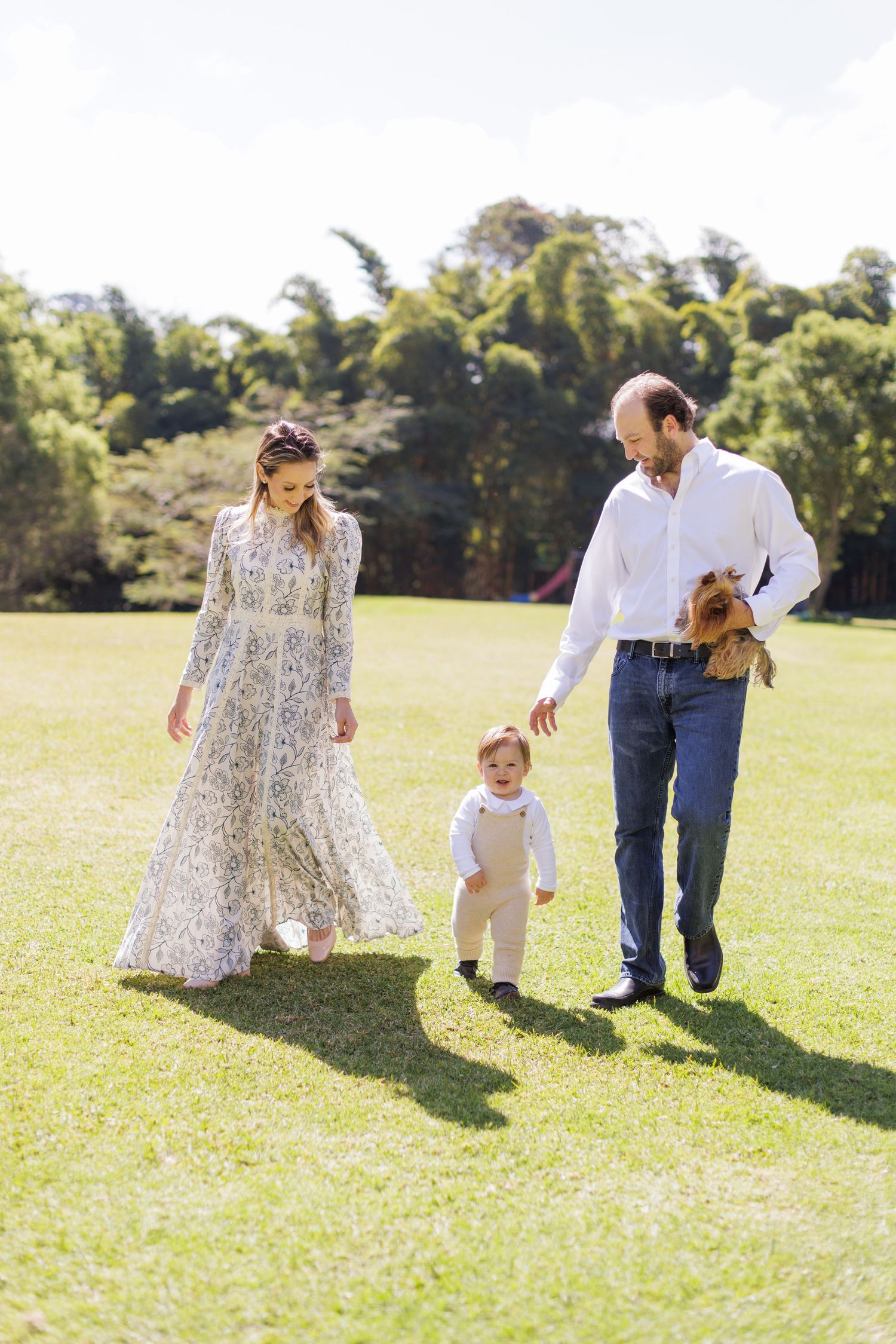 Family walking and playing together on sunny grass field.
