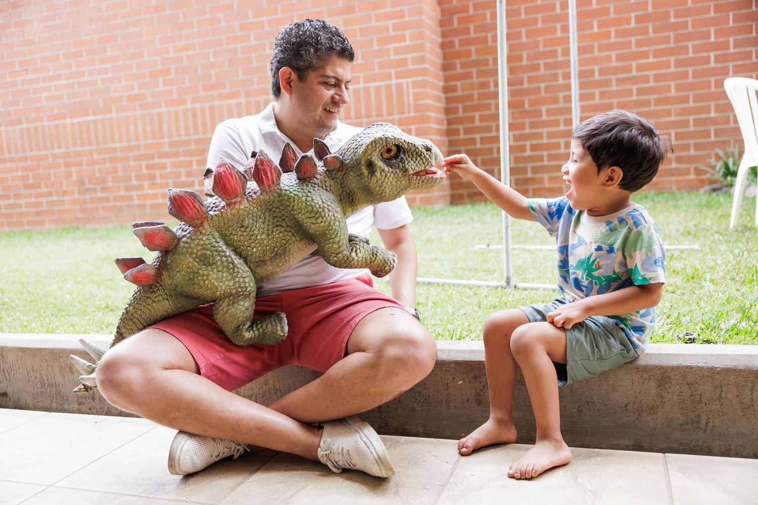 Children sitting outdoors on concrete steps while playing with toys.