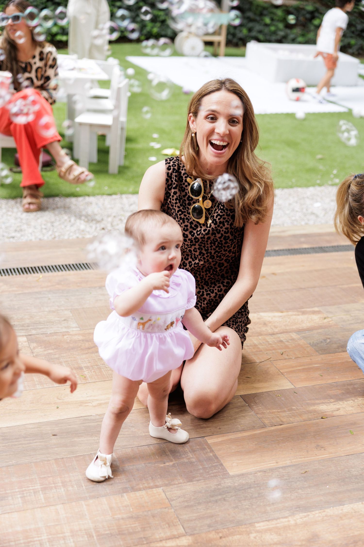Outdoor party scene with bubbles floating through the air on wooden deck.
