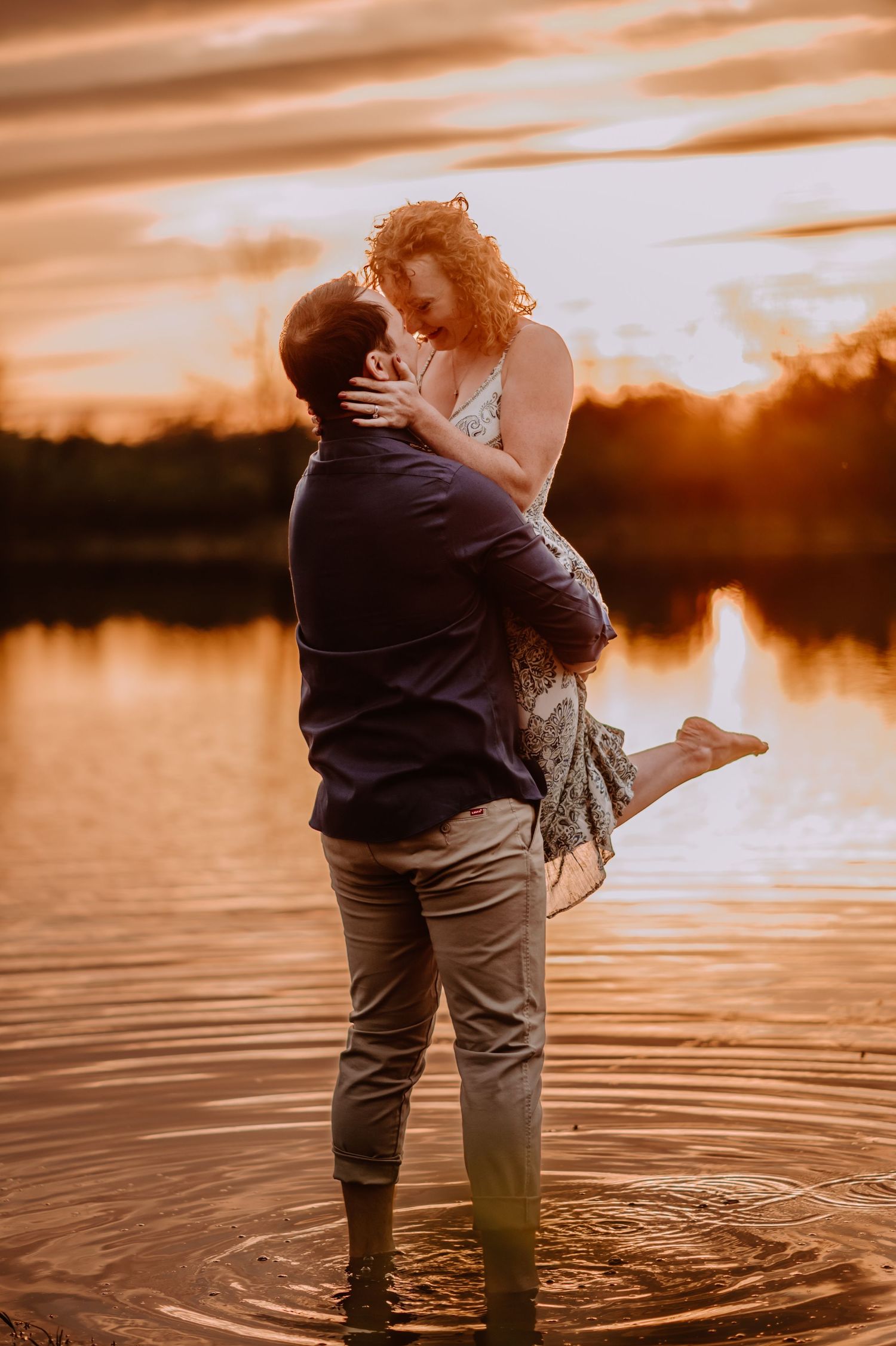 Golden hour engagement session of bride to be being lifted as they dance in the water. Indianapolis wedding photographer