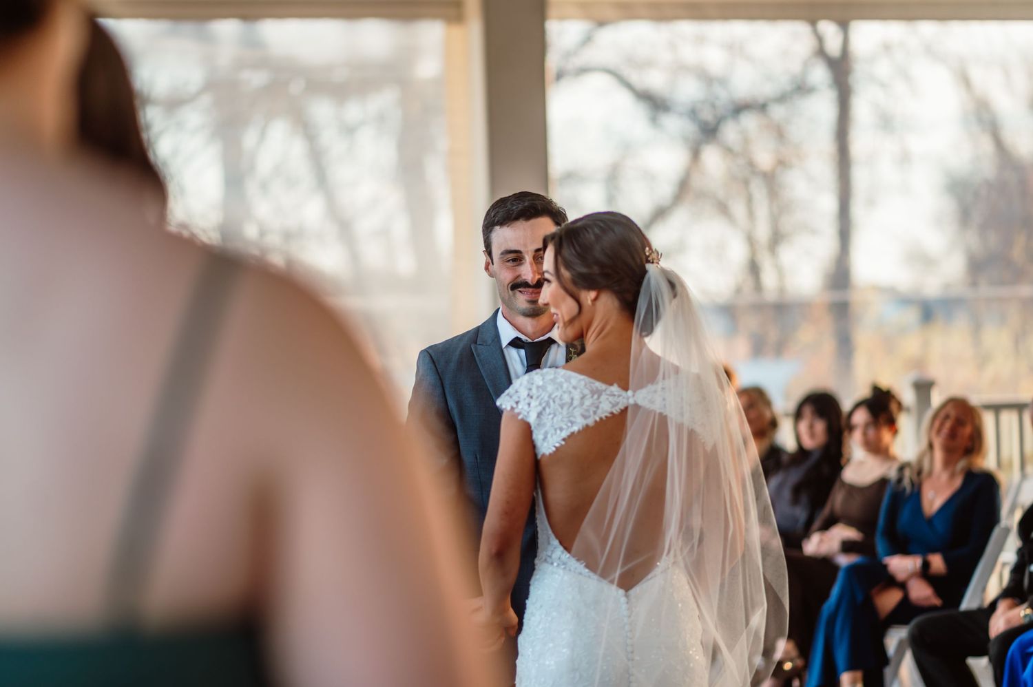 Groom looks lovingly at Bride as they stand at the altar during their ceremony at The Cardinal Room in Whitestown, Indiana