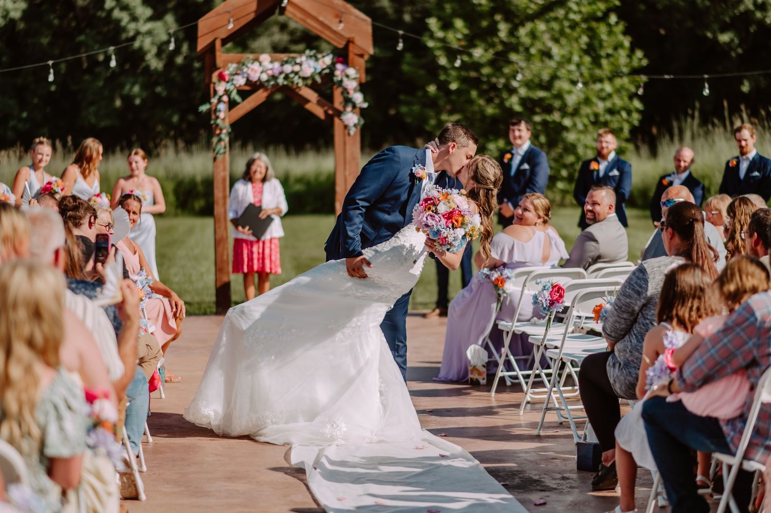 Acorn Ridge Wedding Venue bride and groom sharing a dip and kiss while exiting the ceremony. Indianapolis wedding photographer