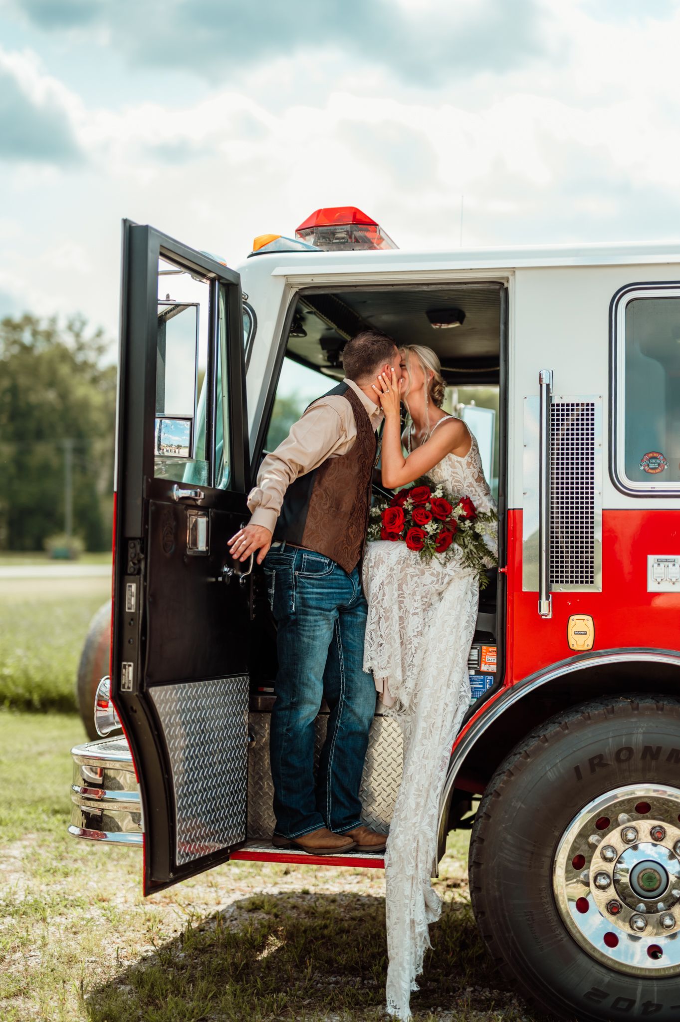 A bride and groom share a kiss in the doorway of a red fire truck on their wedding day in Knox, Indiana
