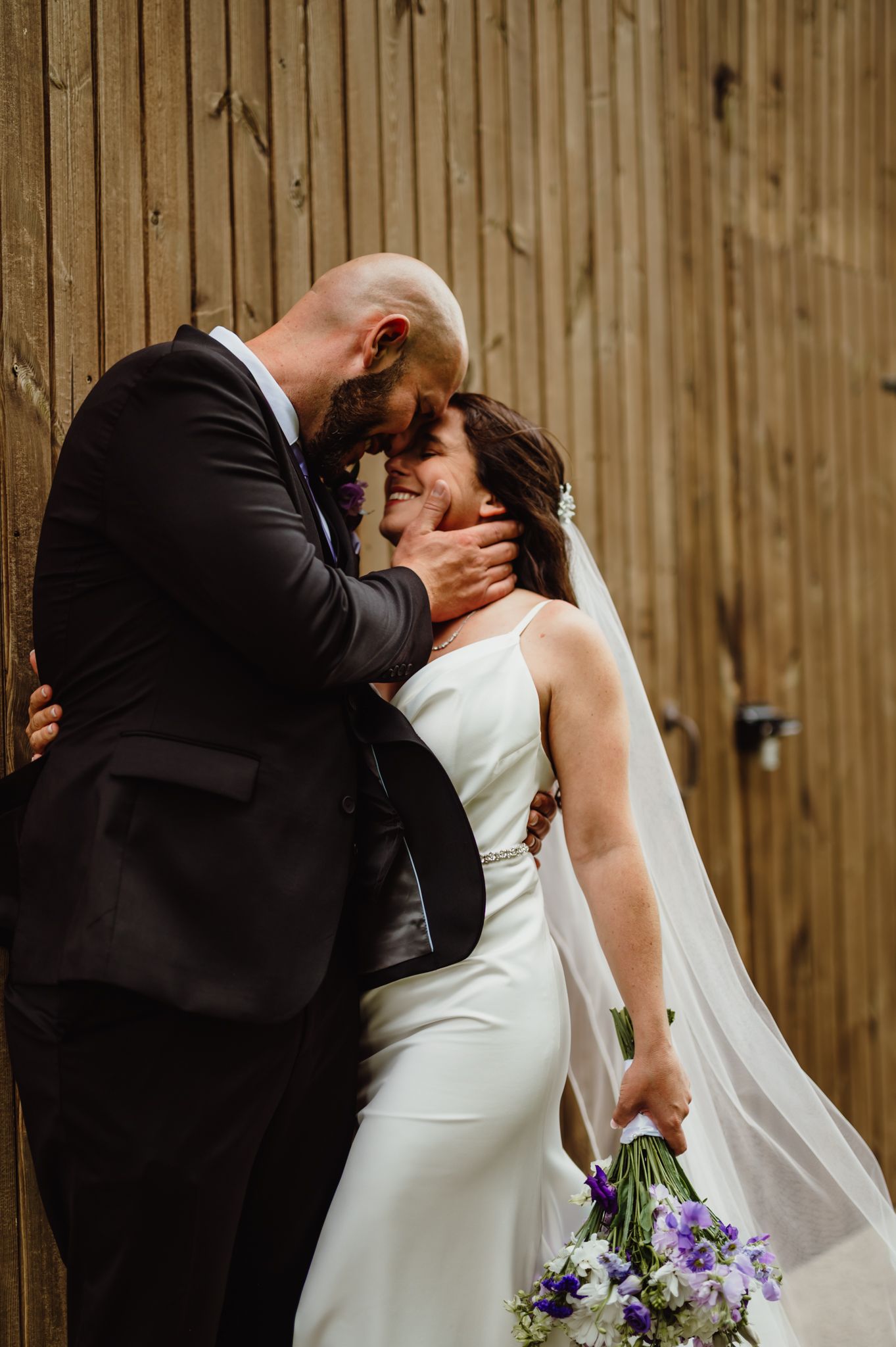 Bride and groom sharing a romantic kiss against the barn wall on the golf course at the Elcona Country Club in Bristol, Indiana