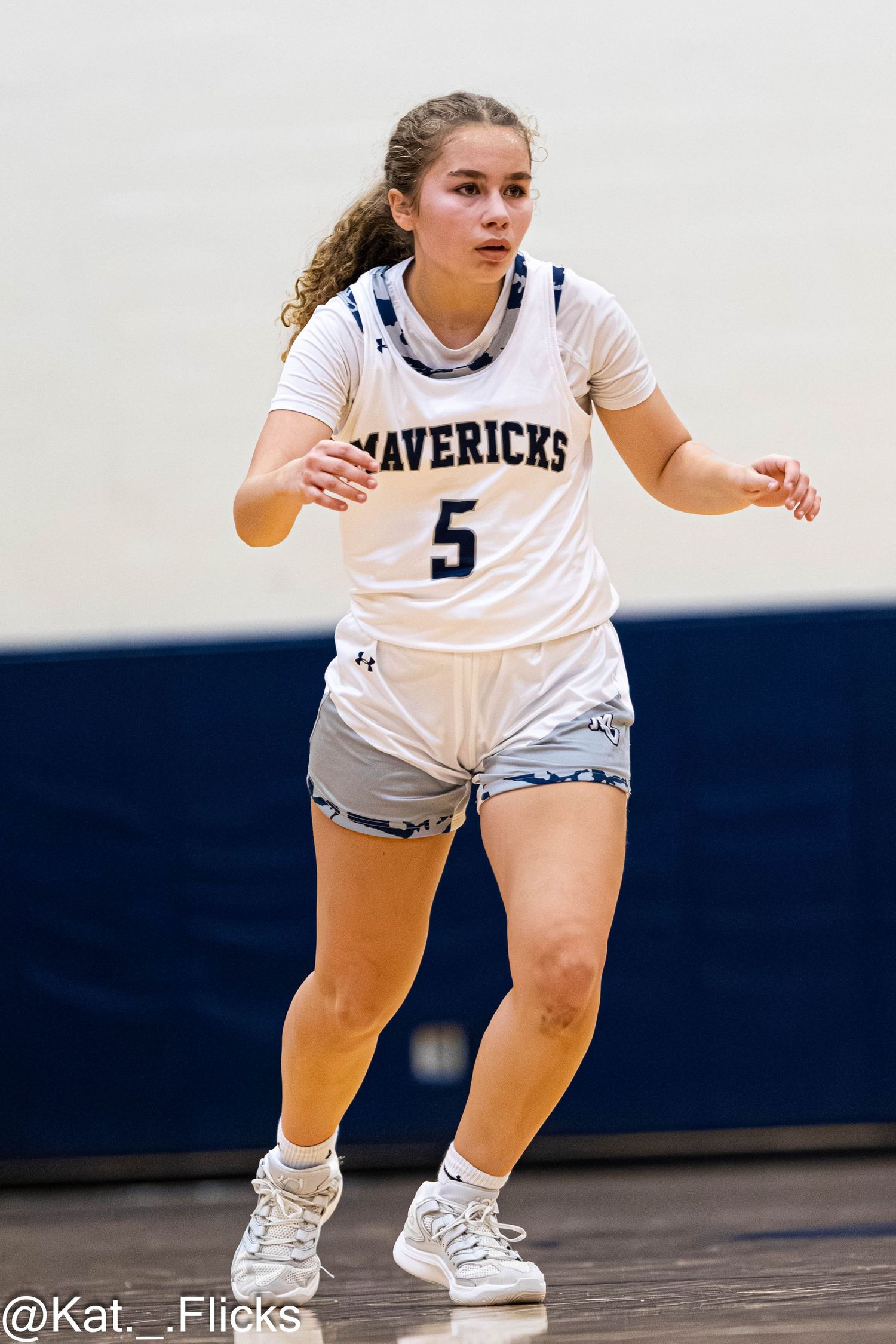 Female basketball player #5 in Mavericks uniform dribbles on indoor court during a game.