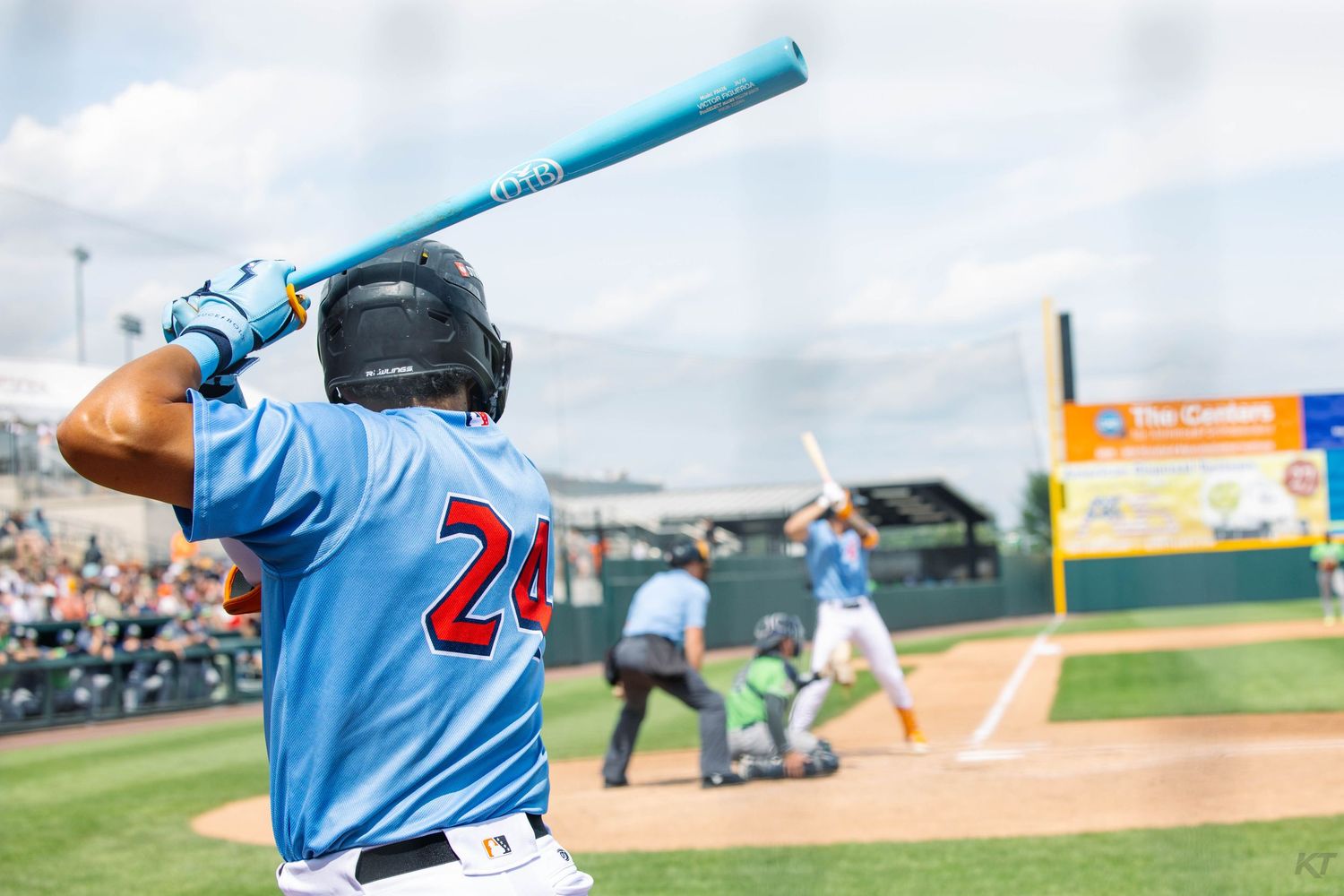 Baseball batter in light blue jersey number 24 in batting stance awaiting a pitch.