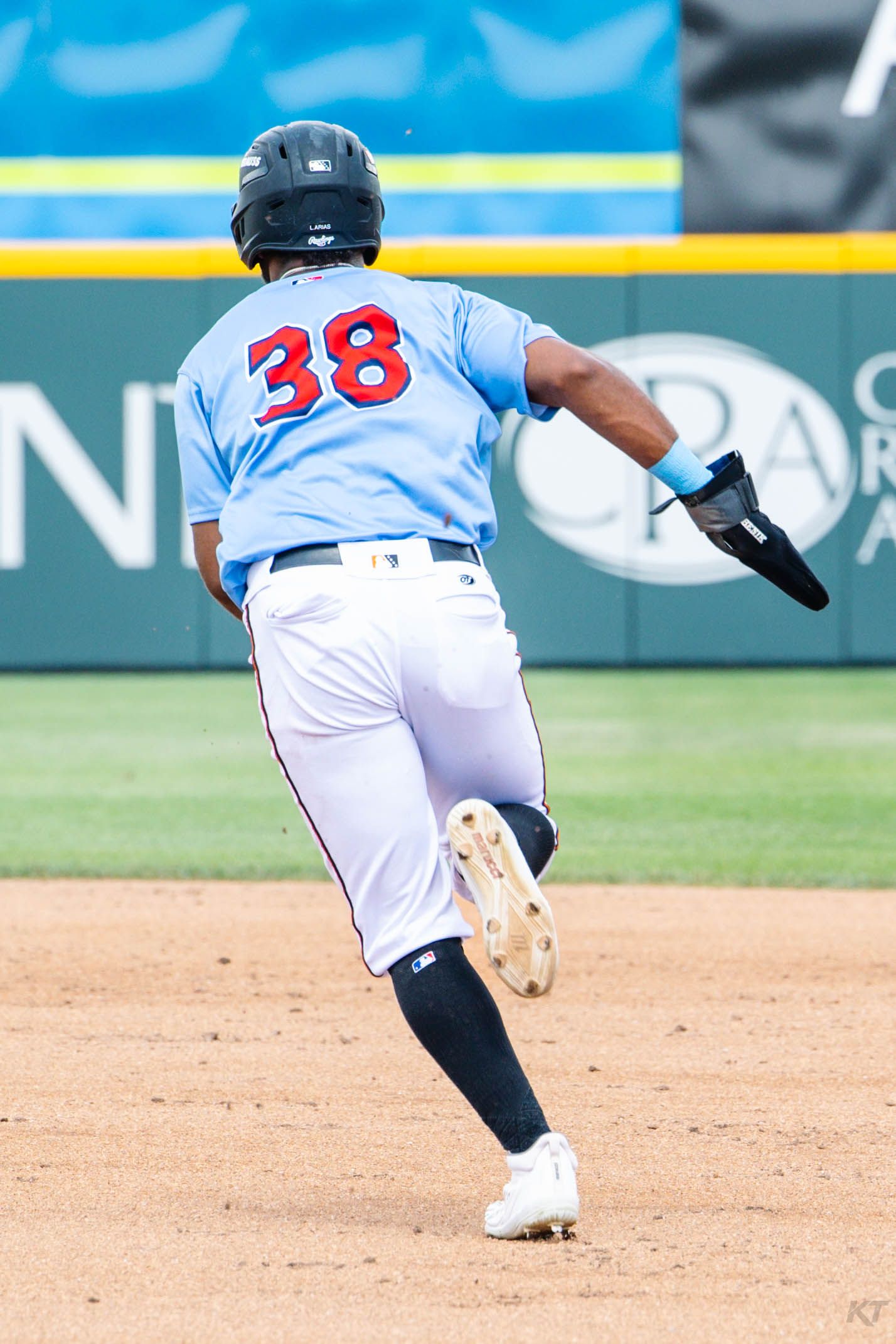 Baseball player #38 in light blue jersey sprints the bases during a professional game.