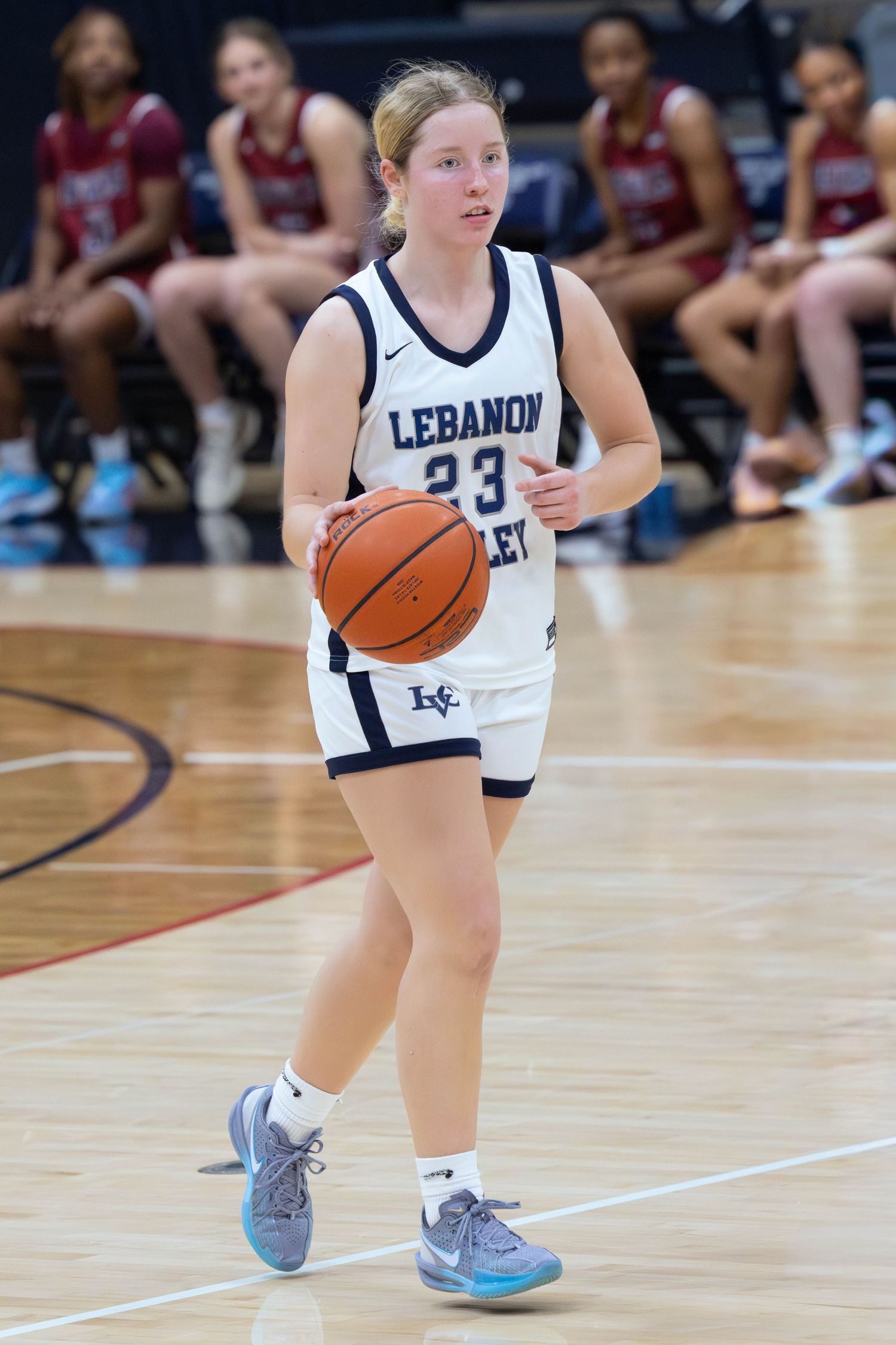 Lebanon Valley College #23 women's basketball player dribbles ball during a game in white home uniform.