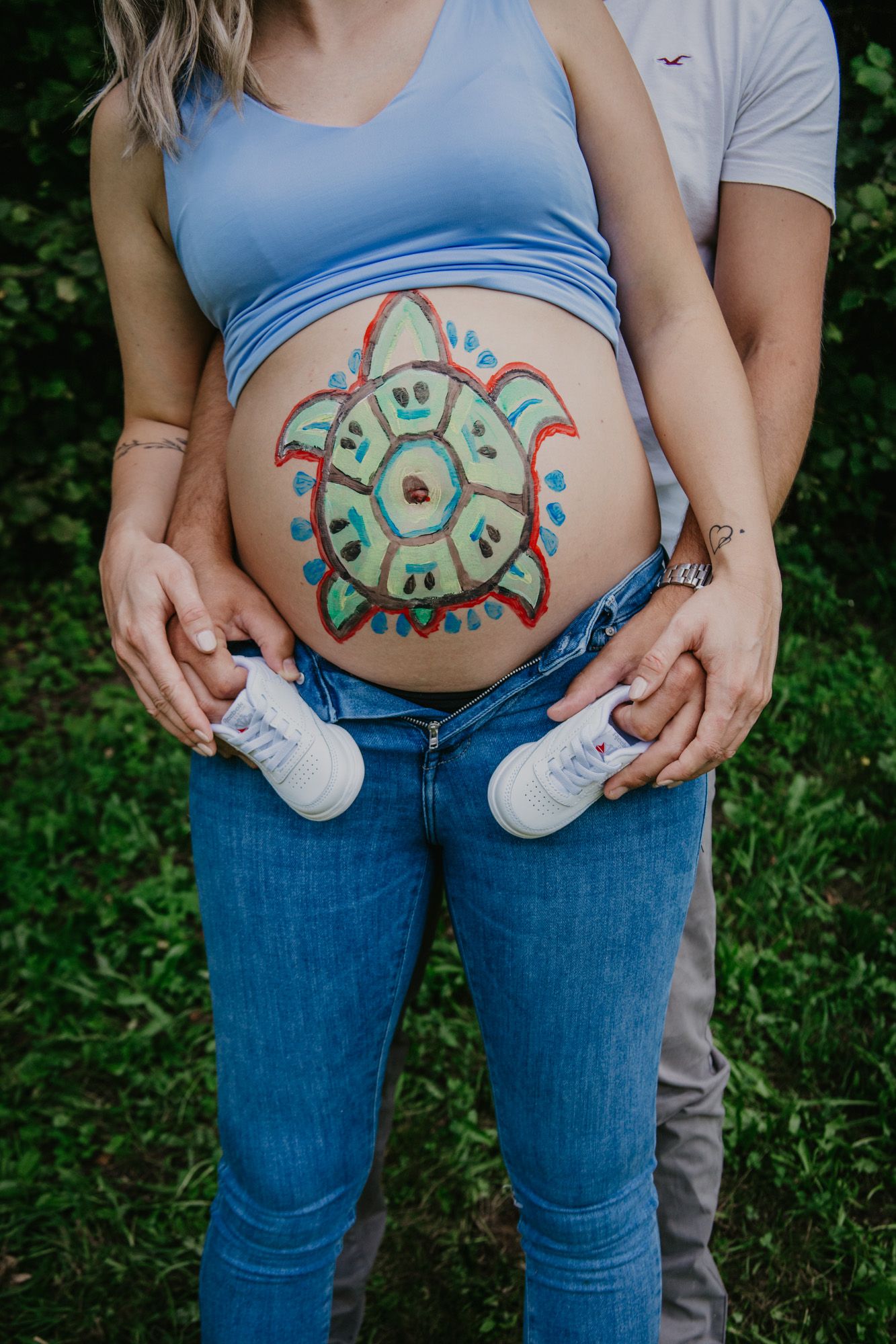 Progression of maternity photos showing painted belly art and white baby shoes.