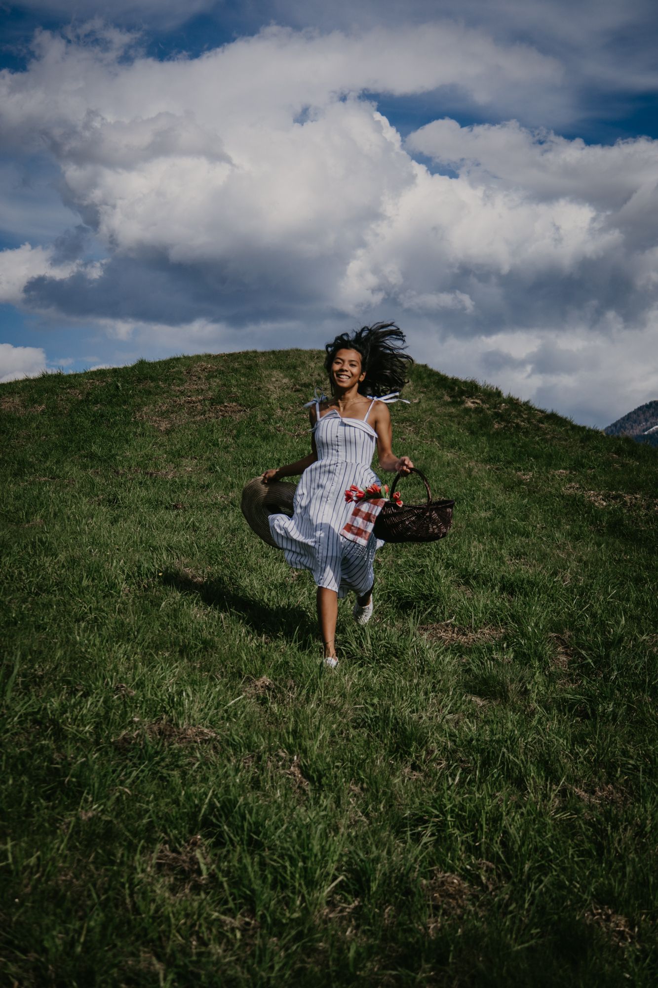 Someone enjoying a picnic while sitting on a scenic grassy hillside with mountain views.