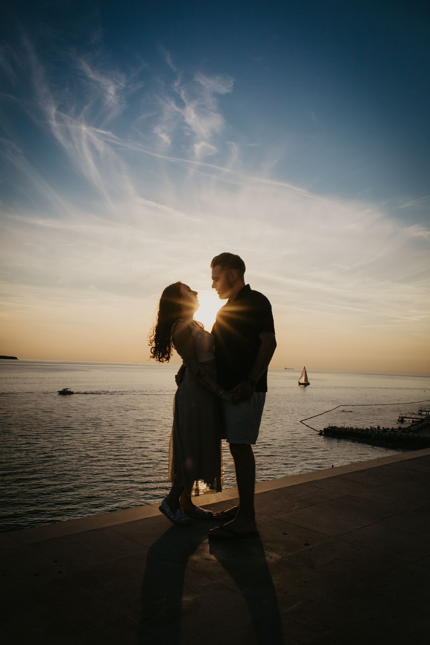 Dramatic backlit portraits of a couple against a sunset seascape.