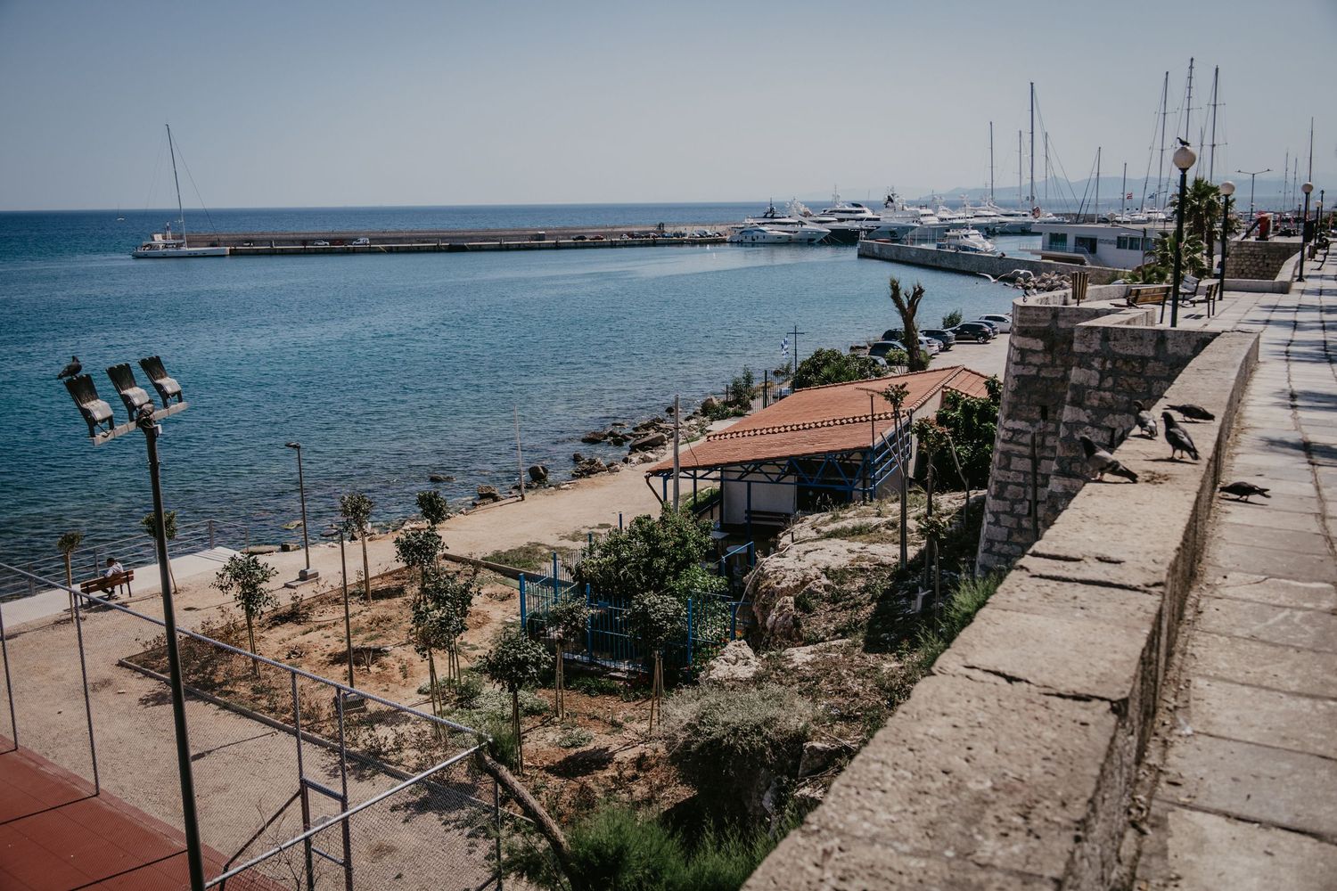 Coastal promenade with Mediterranean Sea views and rocky shoreline.