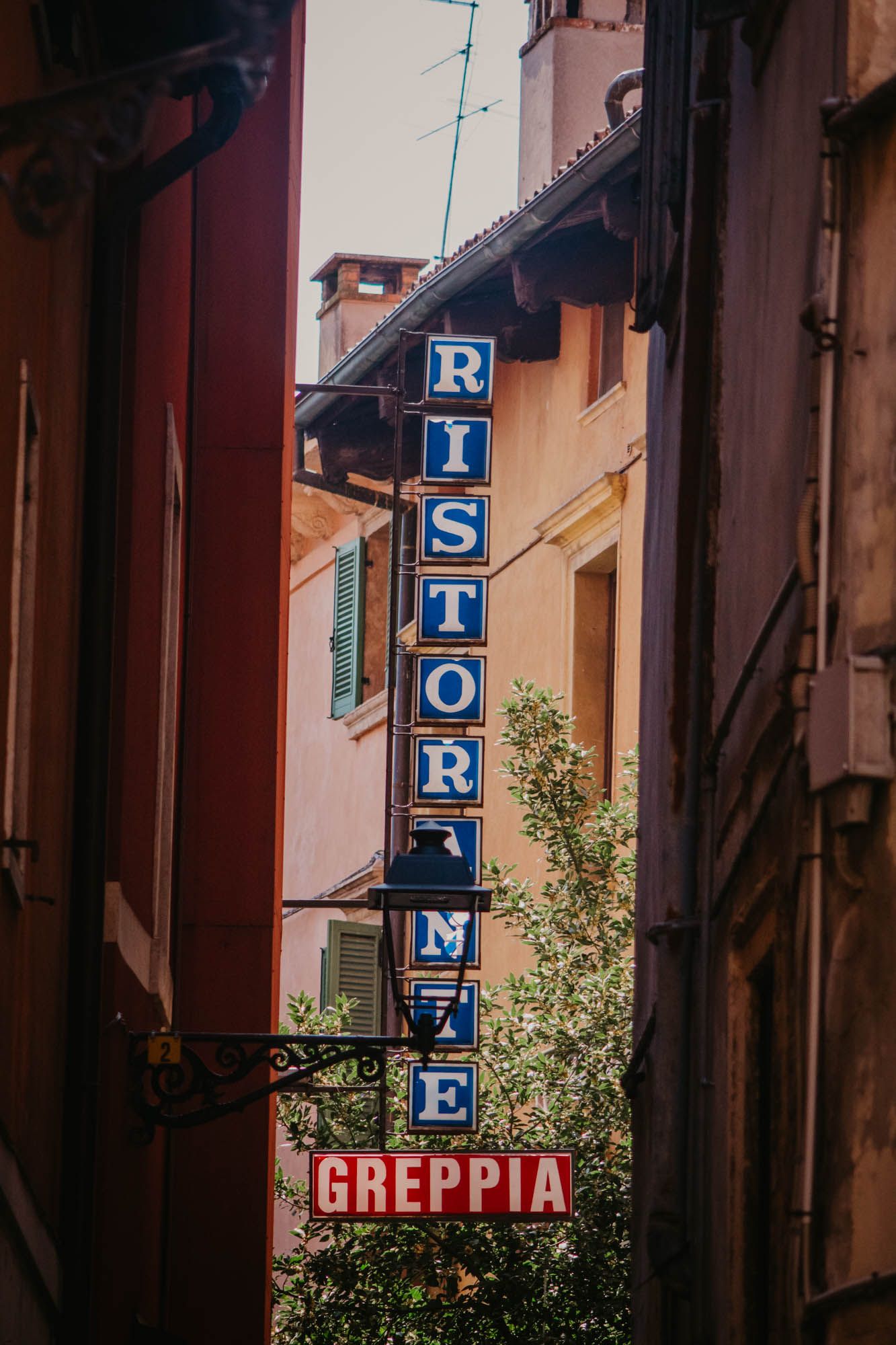 Vintage storefront signs spelling 'Greppia' on traditional Italian building facades.