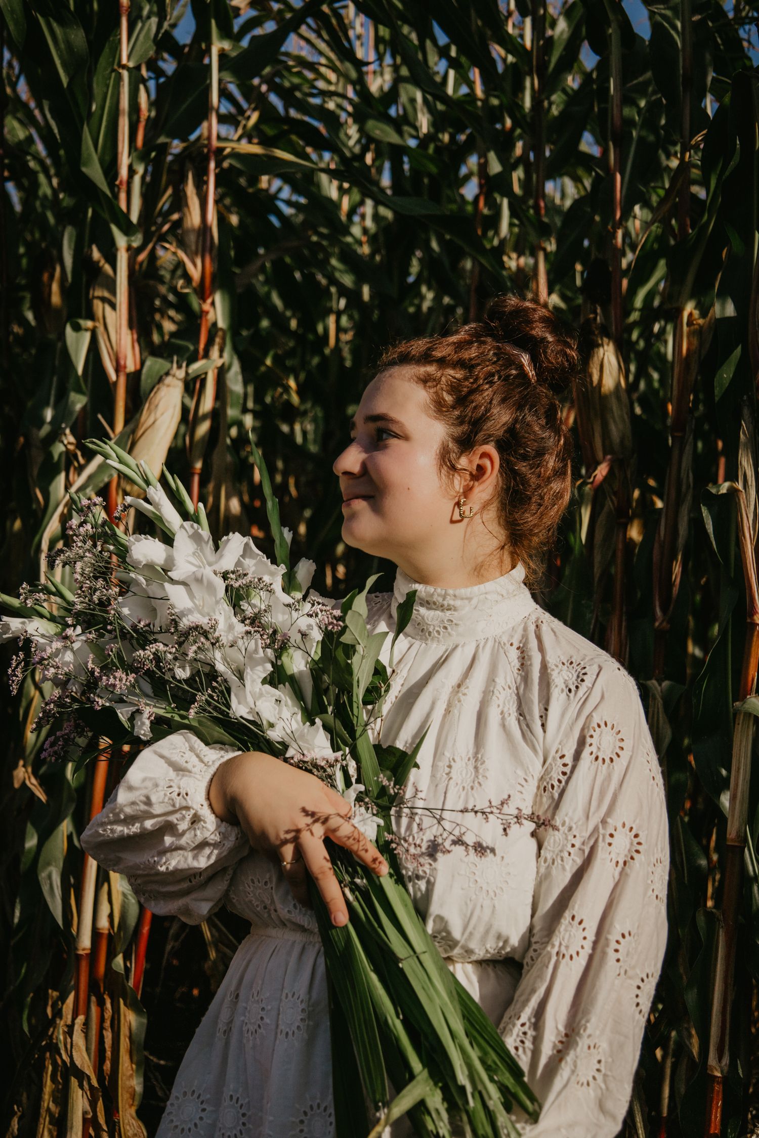 Vintage-style portrait in a cornfield featuring white lace clothing and dramatic lighting.