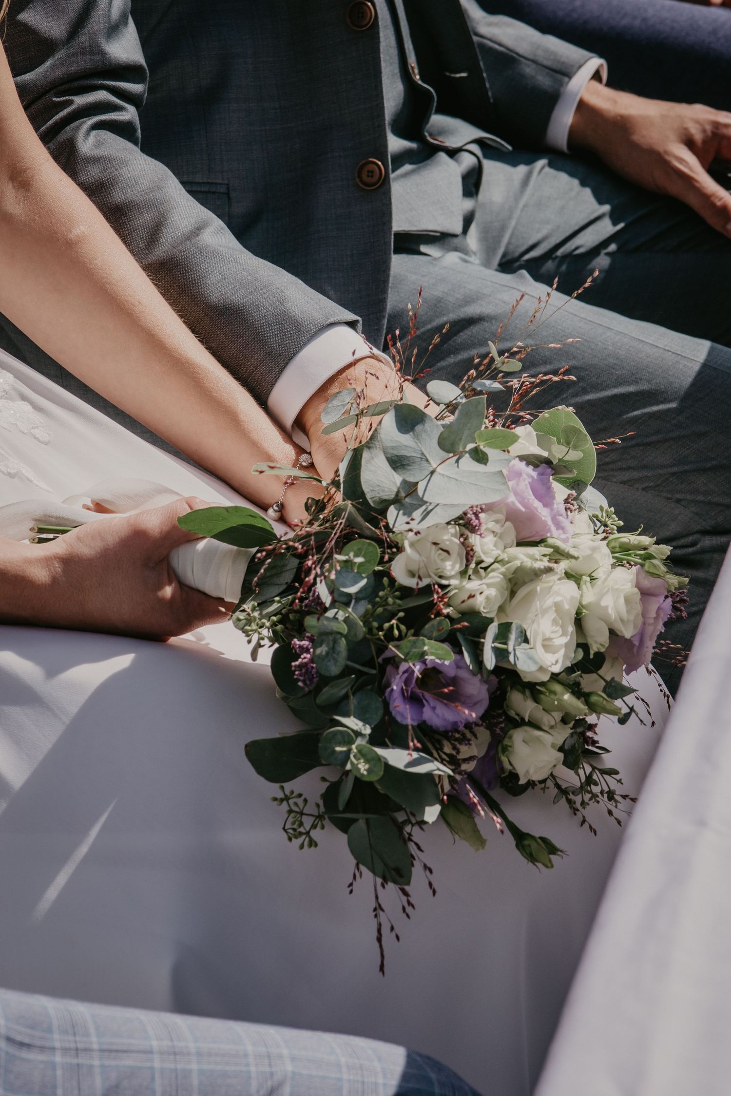 Elegant purple and white floral bouquet resting on white fabric.
