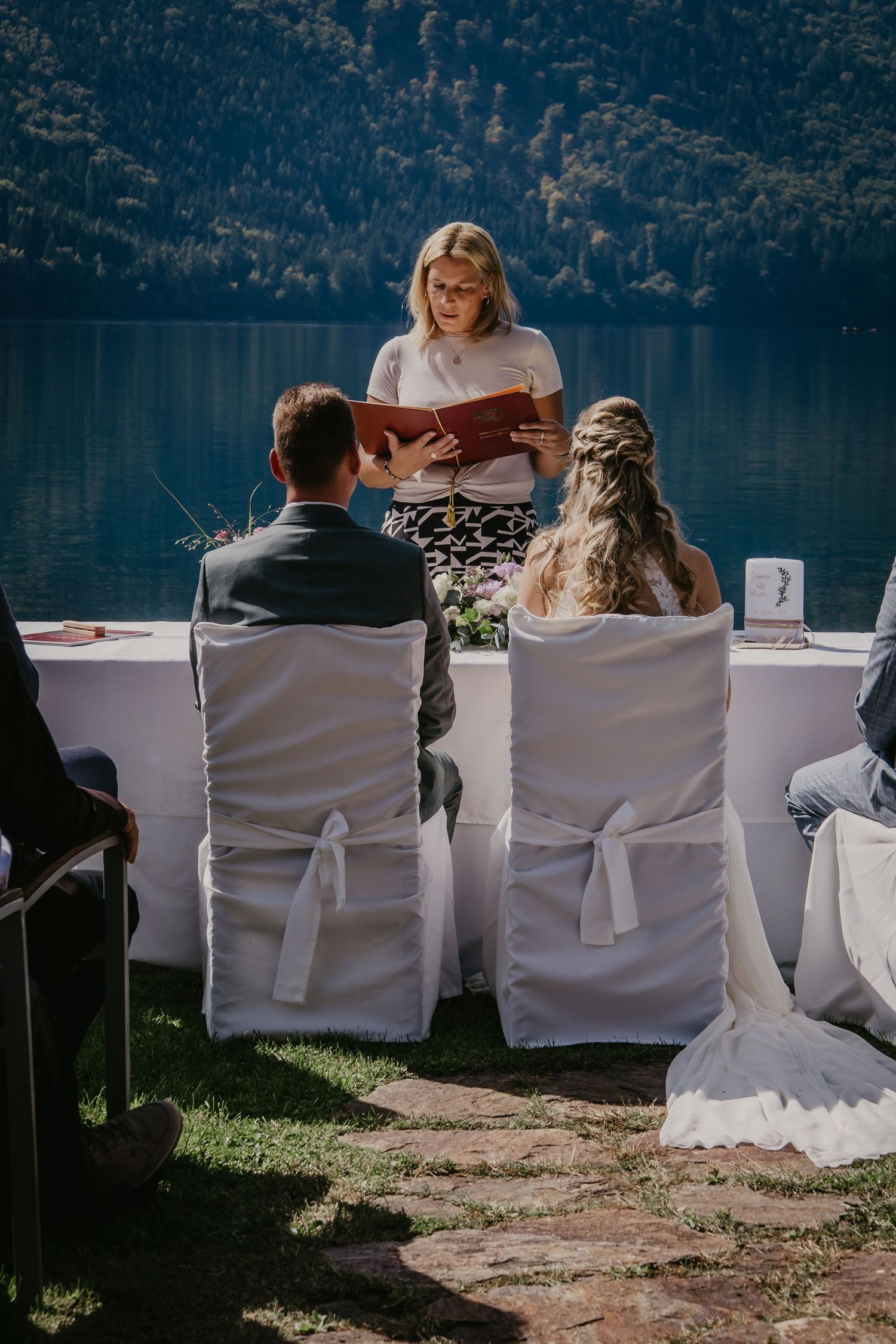Wedding ceremony seating arranged along a lakeside with mountain backdrop.