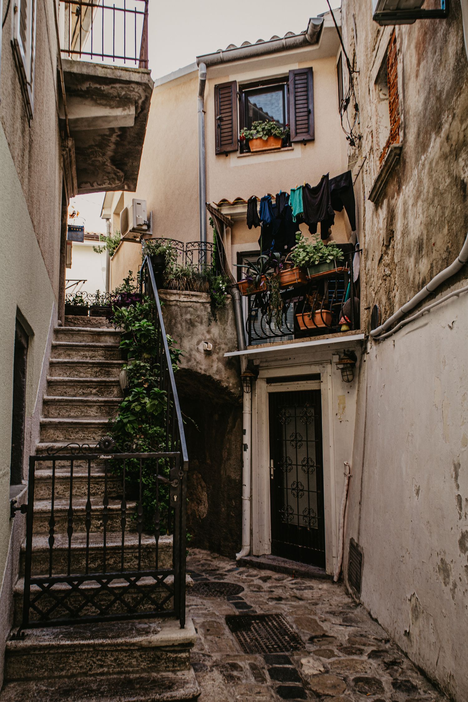 Narrow alleyway with rustic stone stairs and old buildings in a Mediterranean village.