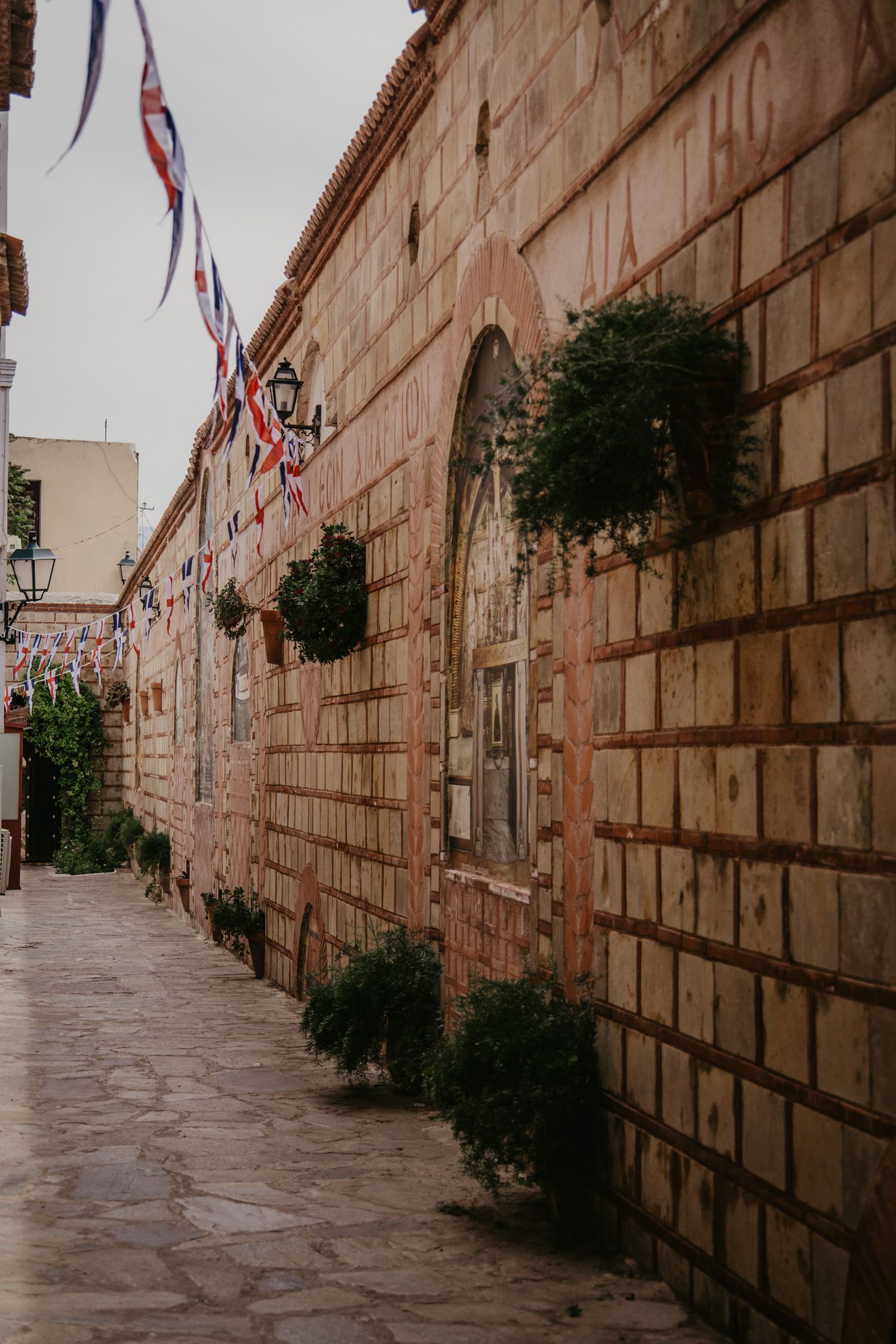 Historic stone corridor decorated with hanging plants and festive banners.