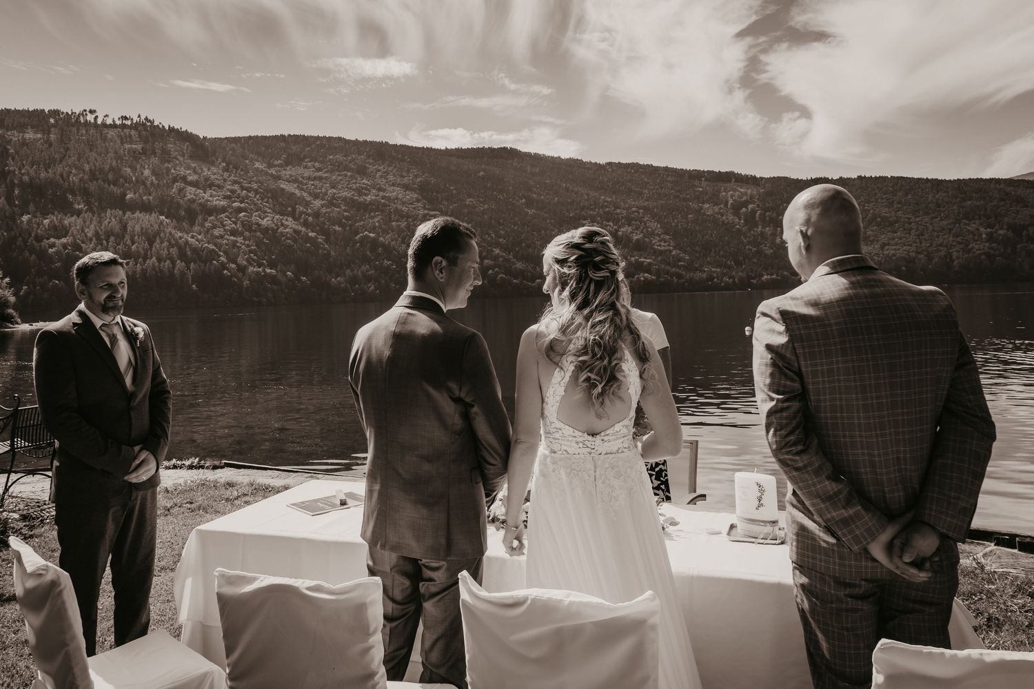 Wedding guests gather at an outdoor ceremony overlooking a scenic mountain lake.