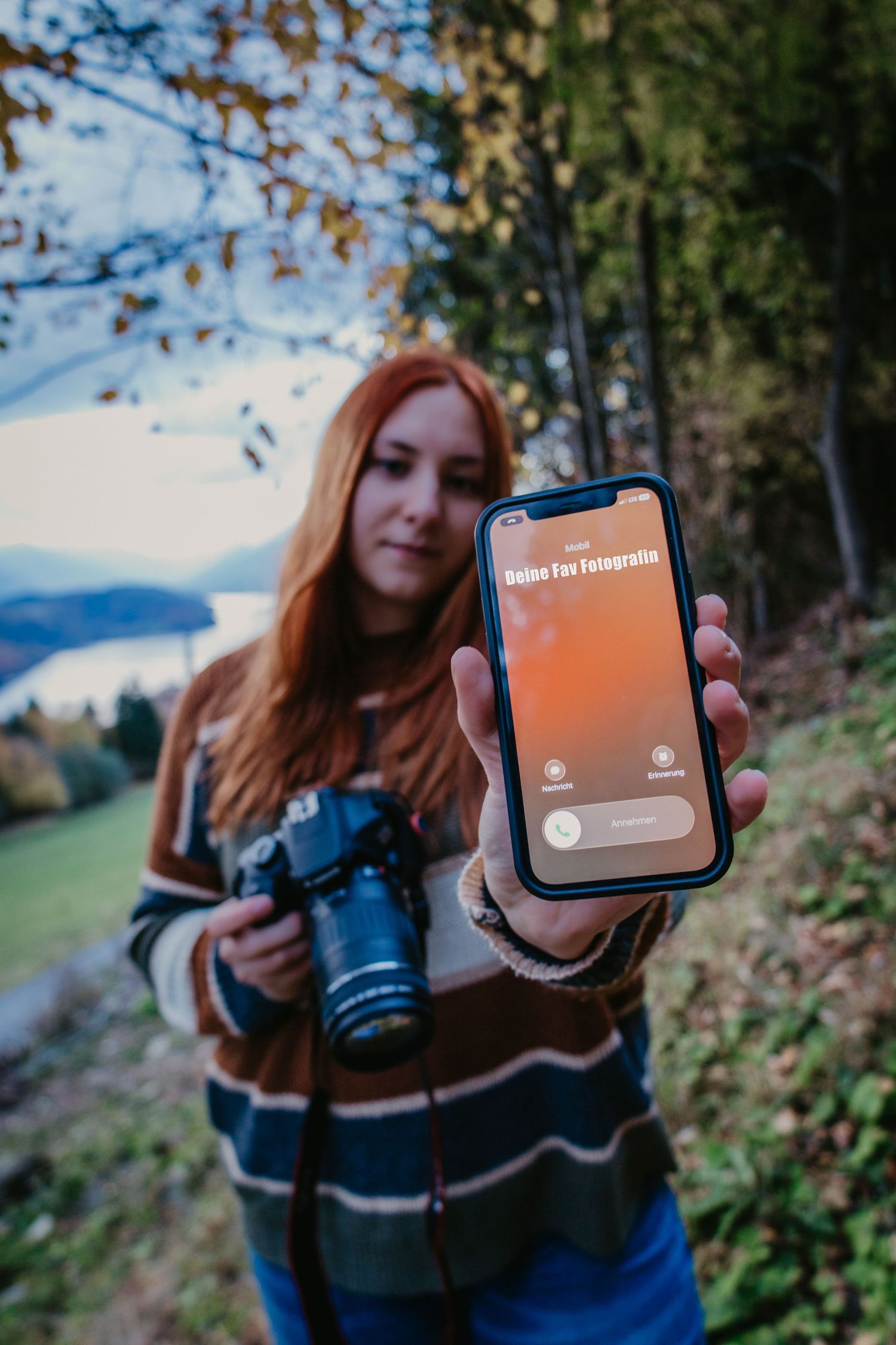 Herbstlicher Hintergrund mit Fotografin die Kamera und Handy hält.