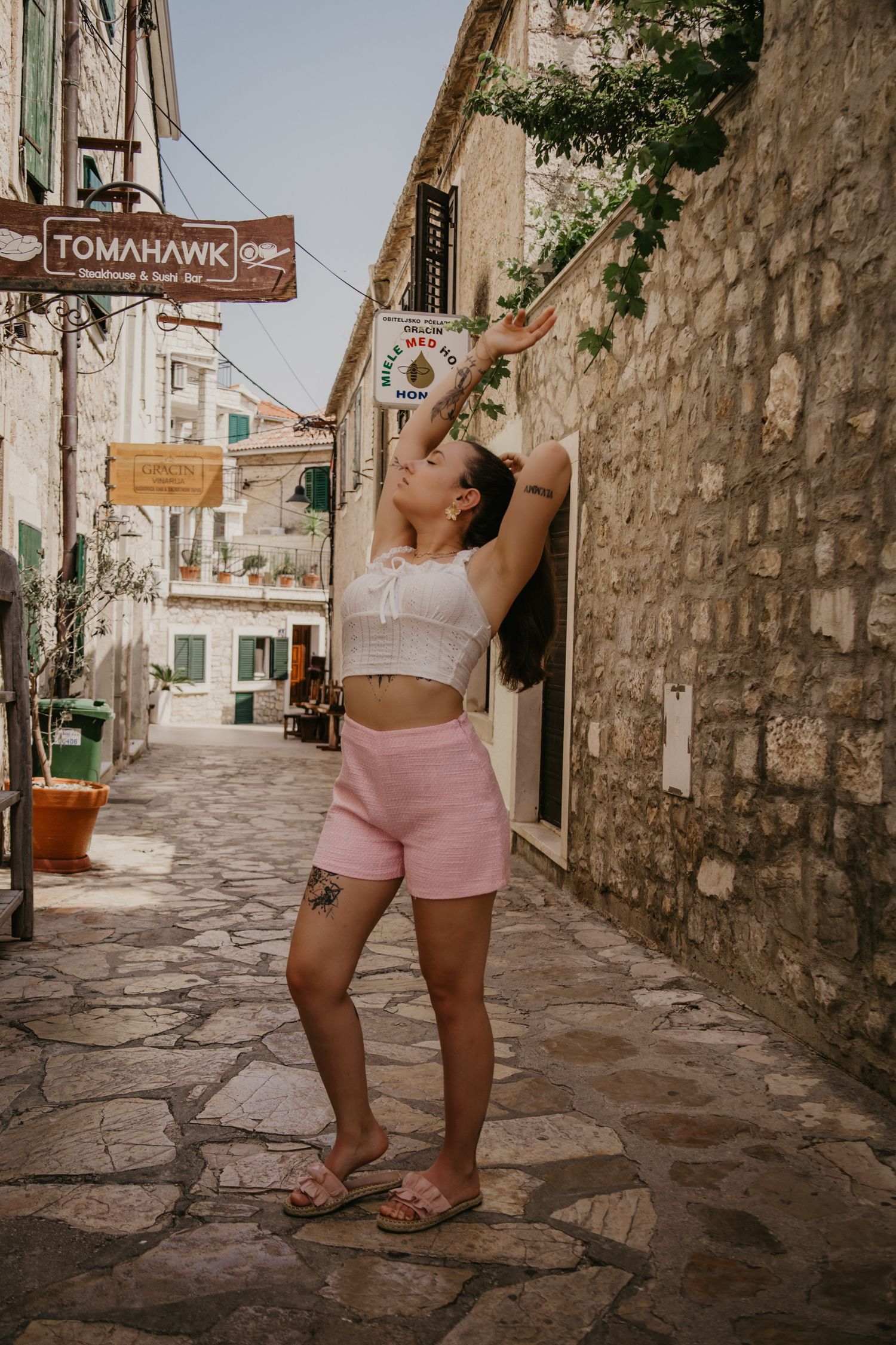 Walking through charming stone-paved Mediterranean street in summer attire.