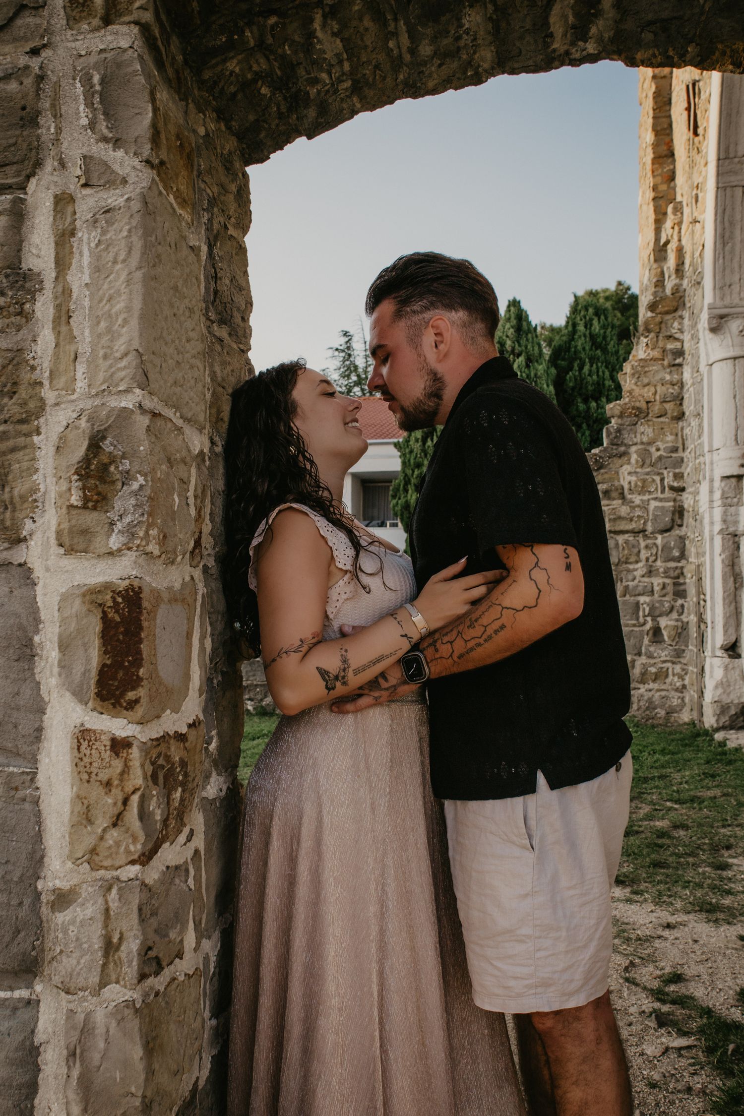Intimate moments captured between a couple in an ancient stone colonnade.