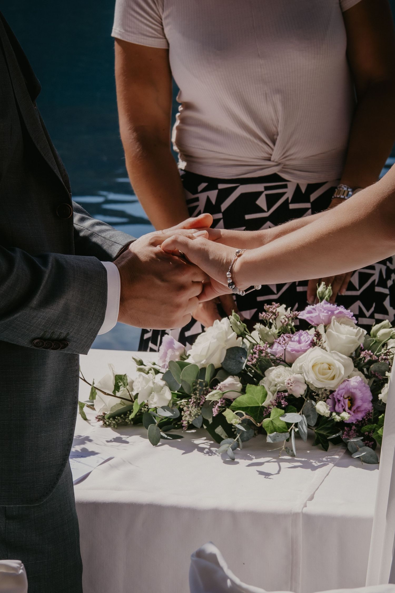 Wedding ceremony table decorated with white and purple floral arrangements.