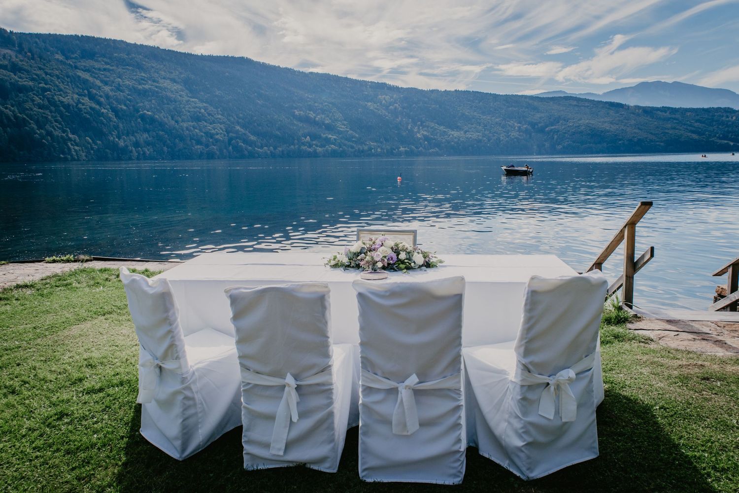 Wedding reception setup overlooking a mountain lake with white chair covers.