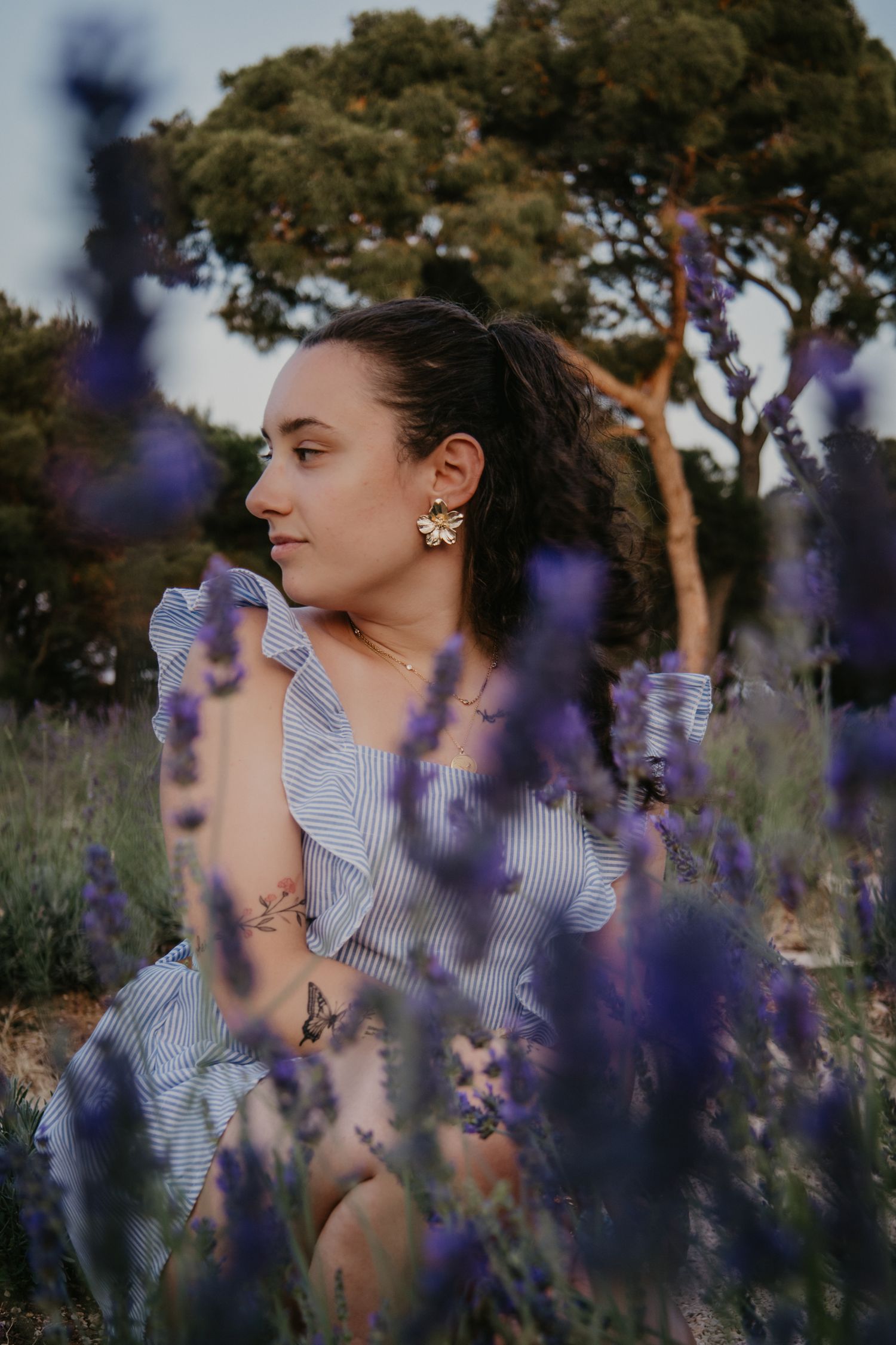 Close-up portraits through purple lavender flowers with pine trees in background.