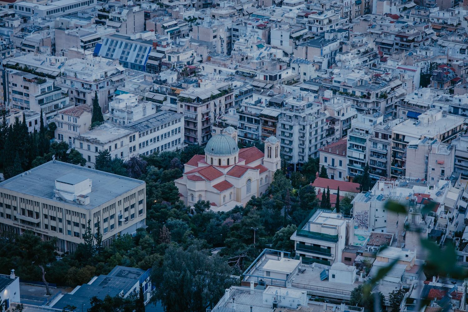 Aerial view of a densely packed coastal Mediterranean city with white buildings stretching to the horizon.