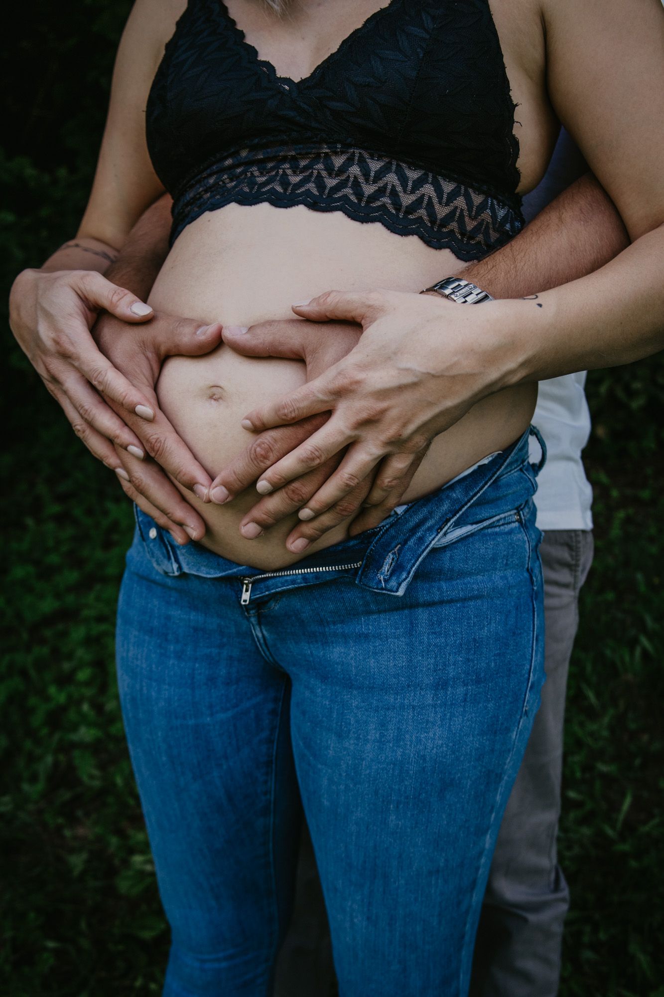 Close-up shots of hands cradling a pregnant belly in blue jeans.